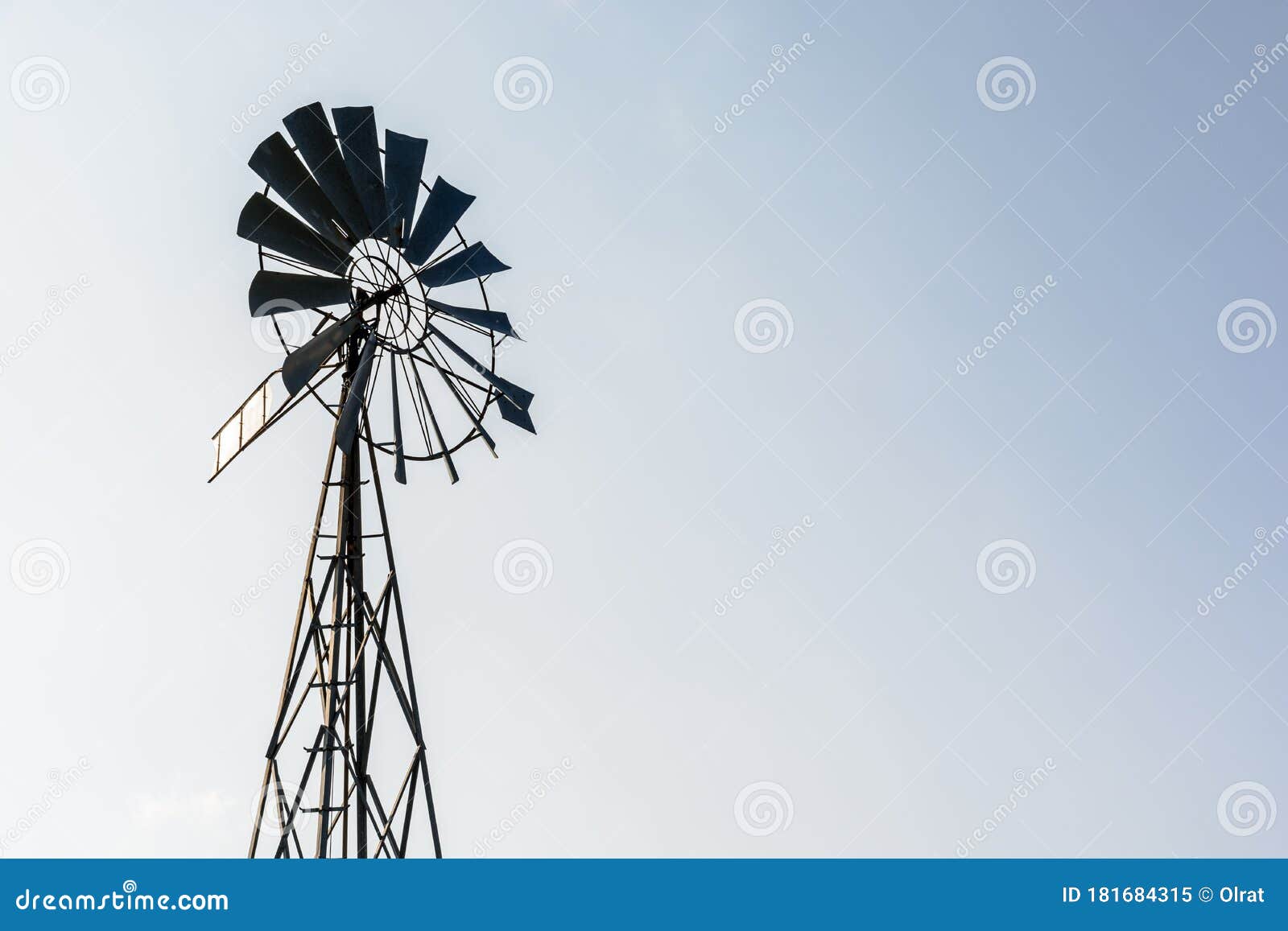 old-fashioned wind pump against pale blue sky