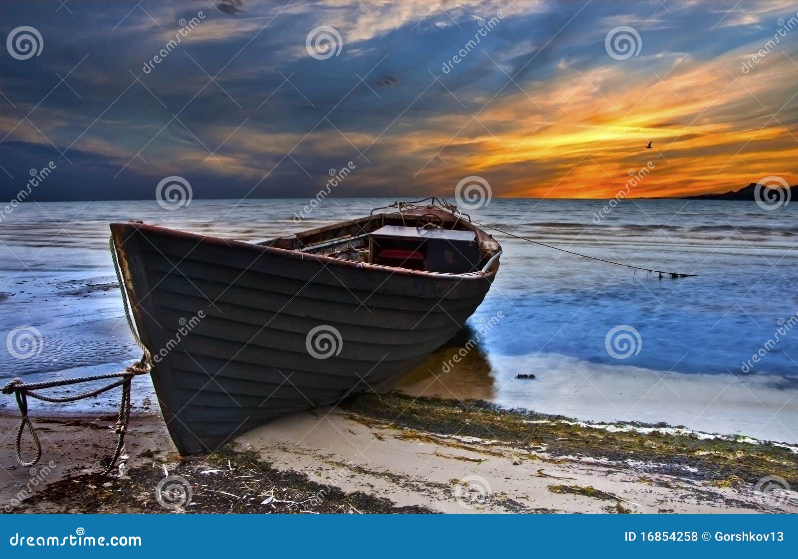 The old fishing boat after storm on a sandy beach of a tropical sea .