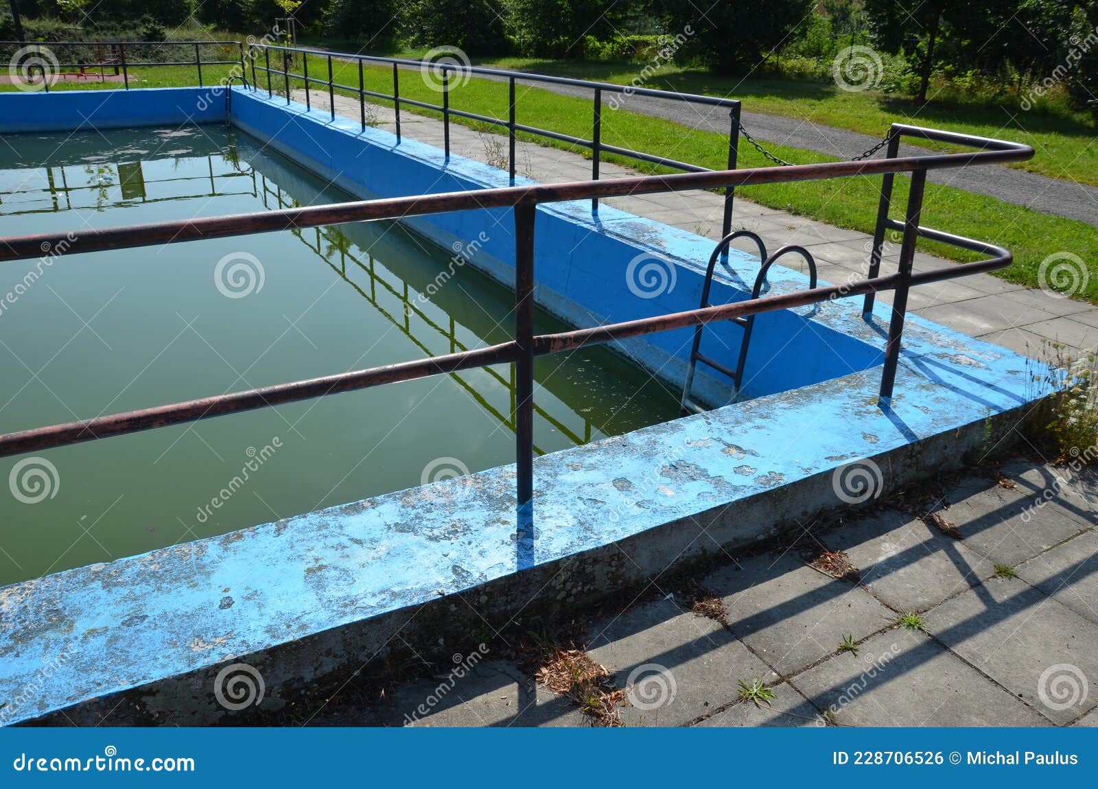 an old half-empty concrete pool on each square. it has railings and steps made of metal. water is used by firefighters against fir