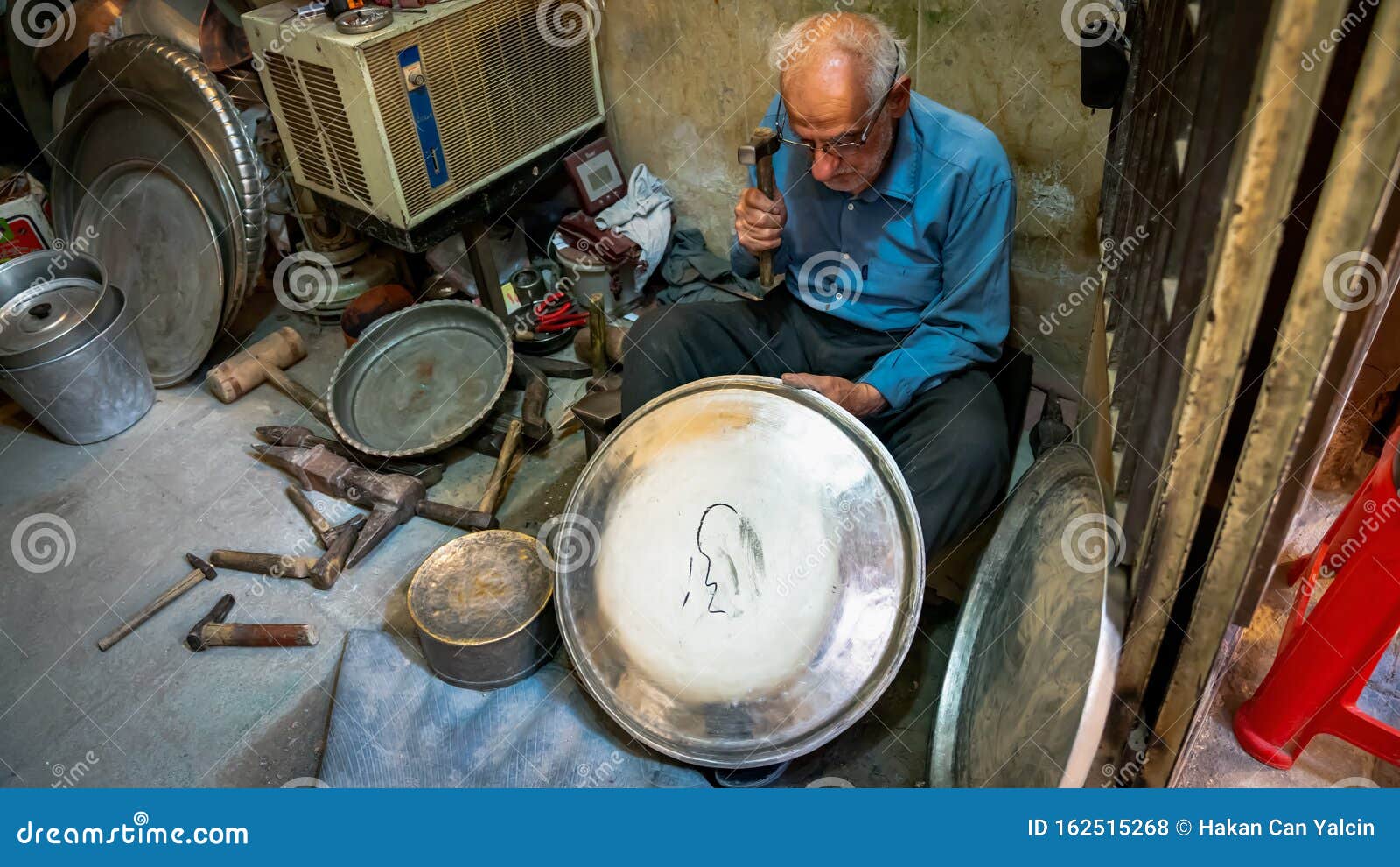 Old Iranian Man Working with His Hammer in a Store with Various Old
