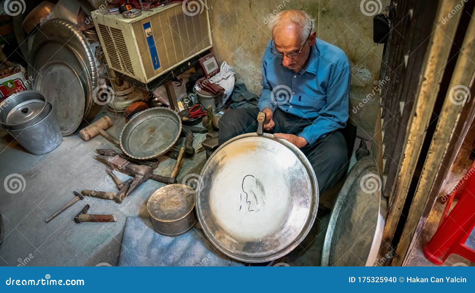 Old Iranian Man Working with His Hammer in a Store with Various Old