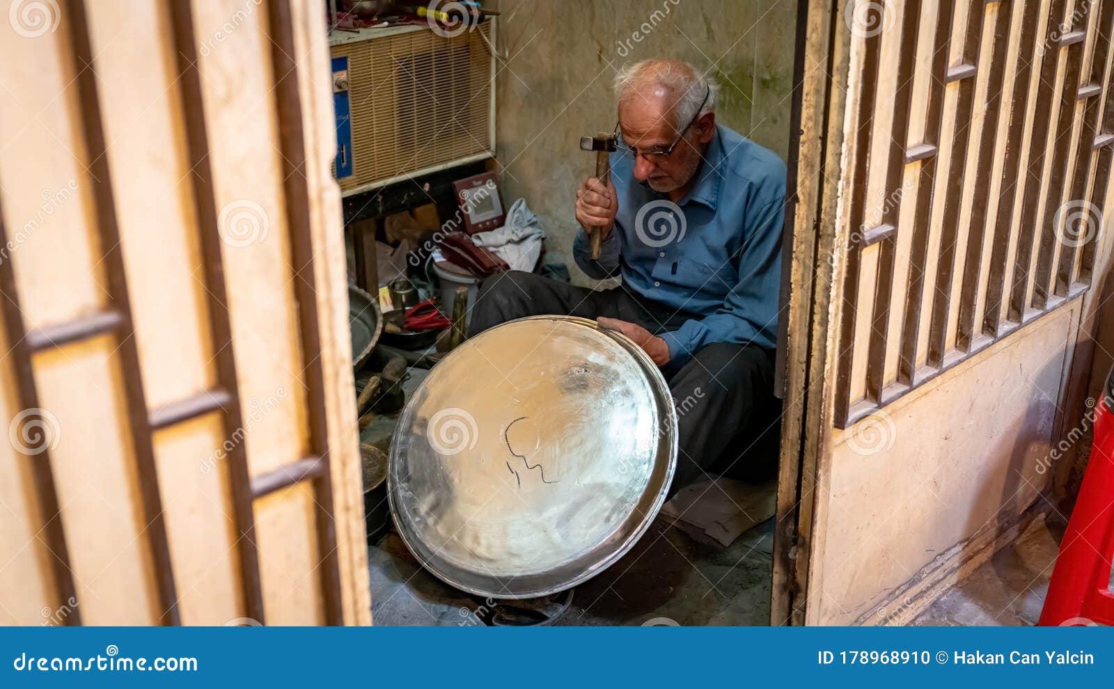 Old Iranian Man Working with His Hammer in a Store with Various Old