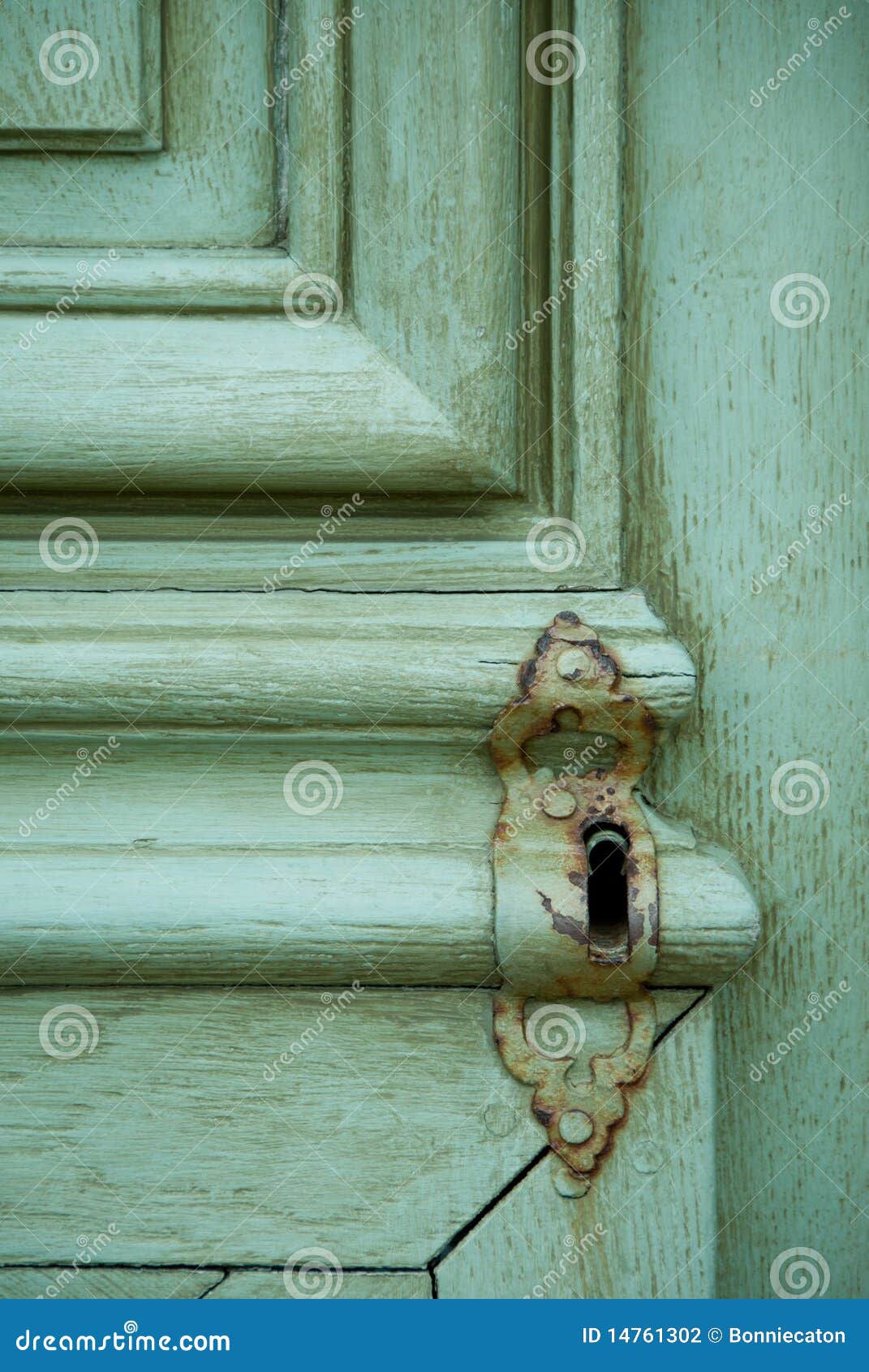 Old Locked Door. Detail shot of an old, rusting keyhole on a heavy wooden door with worn teal-colored paint