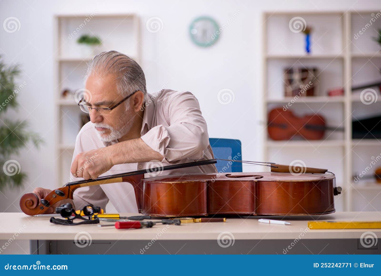 Old Male Repairman Repairing Musical Instruments at Stock