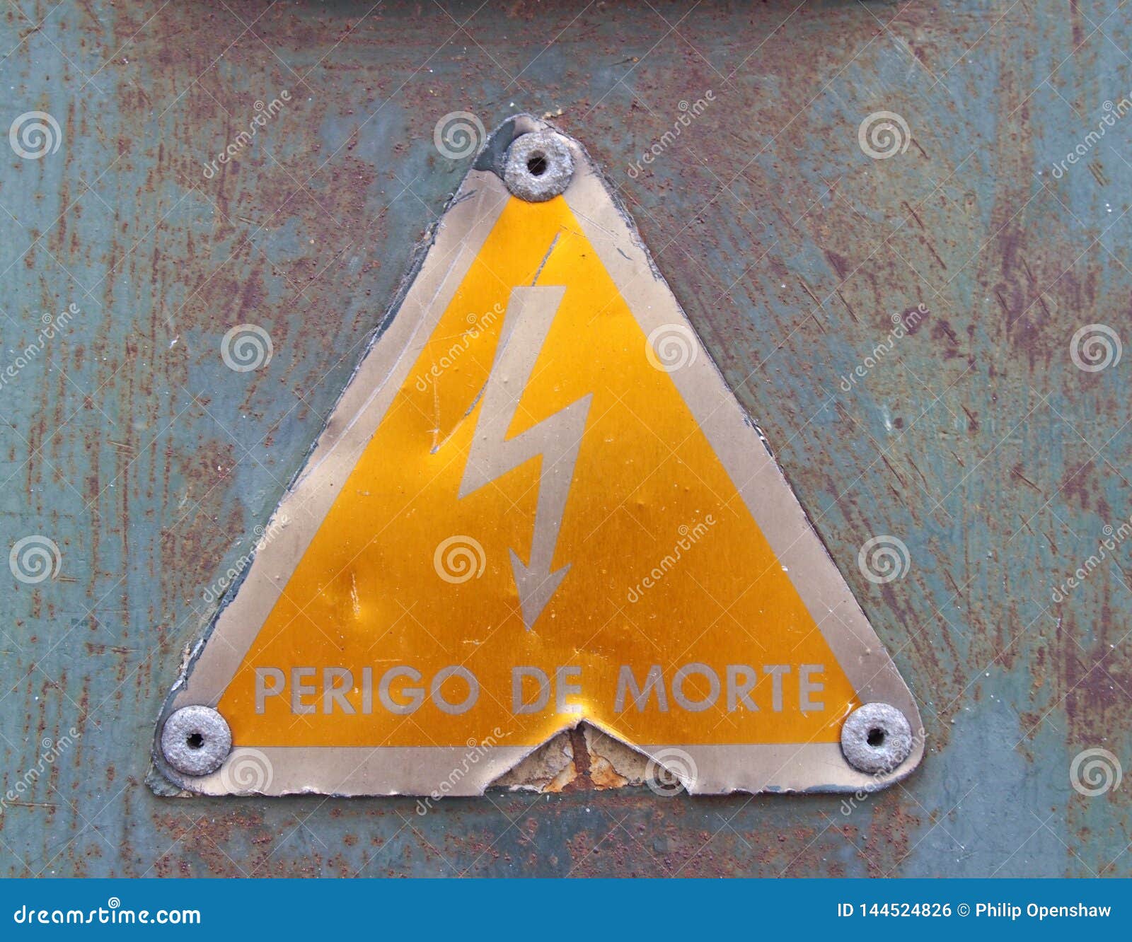 an old metal triangular yellow portuguese electricity safety sign with a lightning bold  reading perigo de morte -