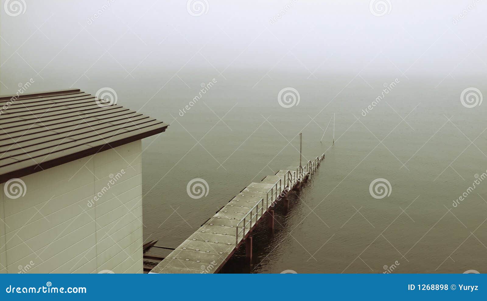 Old pier in mist. Old sinking pier and building on the misty lake shore