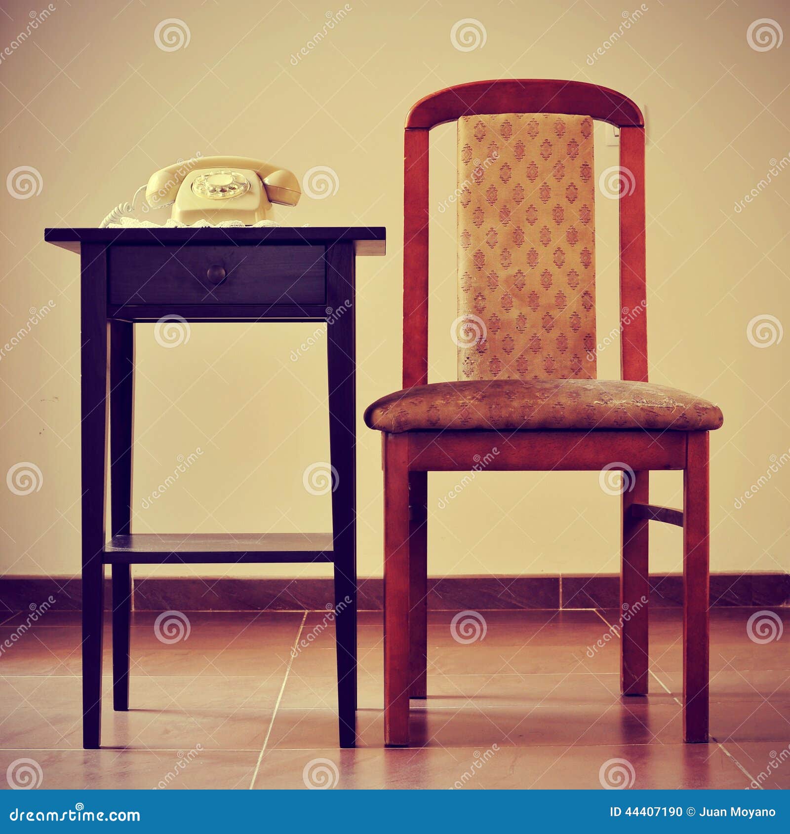 old rotary dial telephone on a table next to a chair, with a retro effect