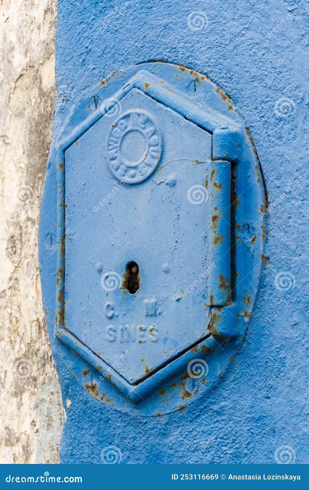 old rusty blue painted iron lid of a valve box of the servico de agua public water supply