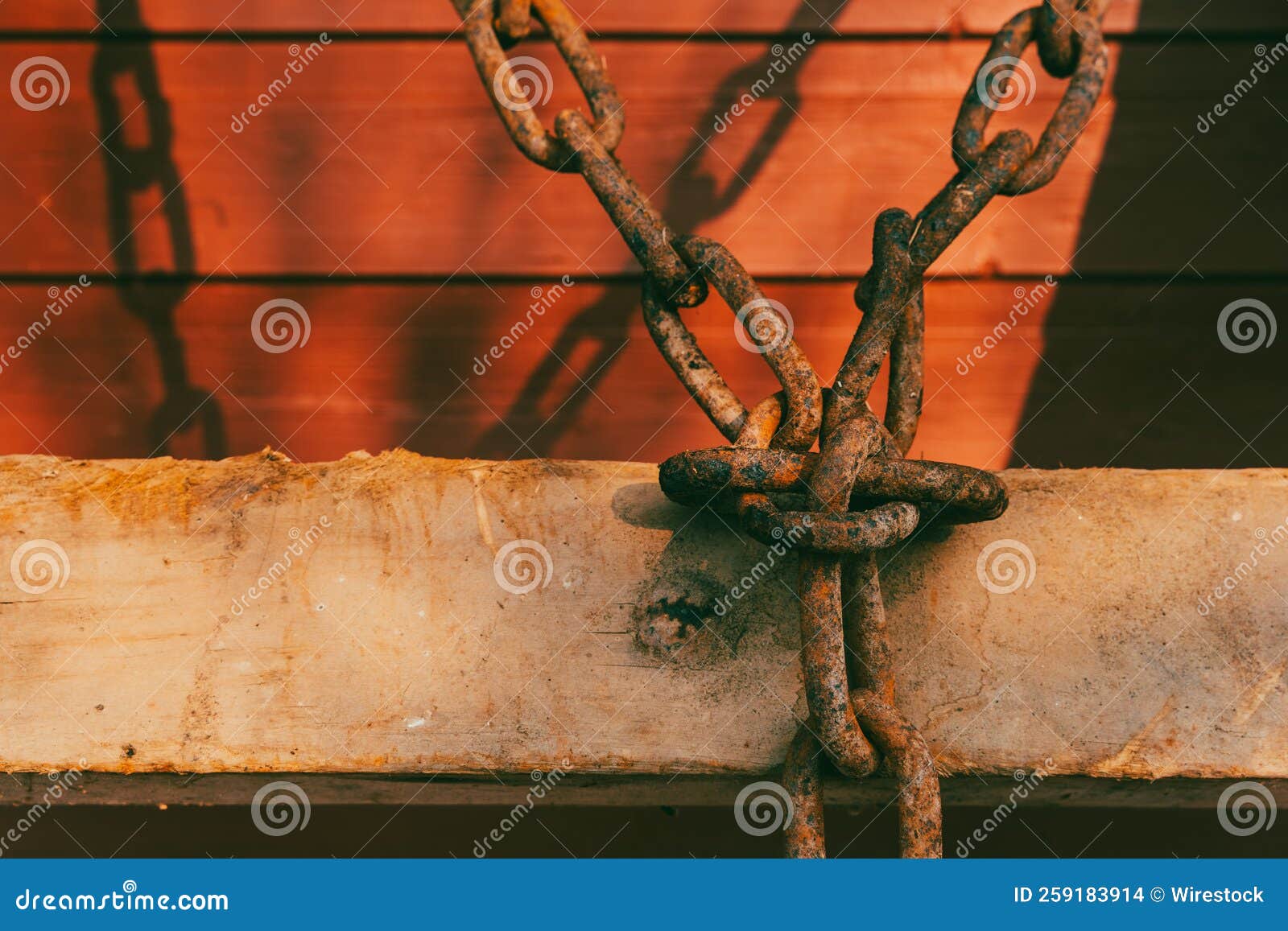 old rusty chain from a timber sledge casting shadows on a wall