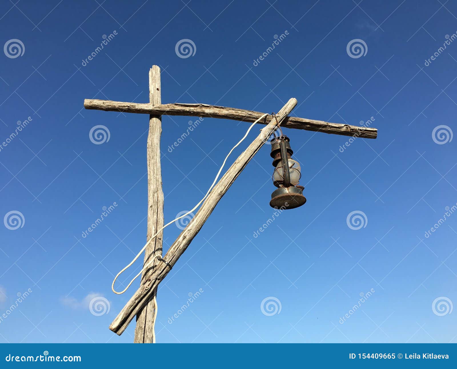old rusty kerosene lamp with a white wire on a street wooden post crane