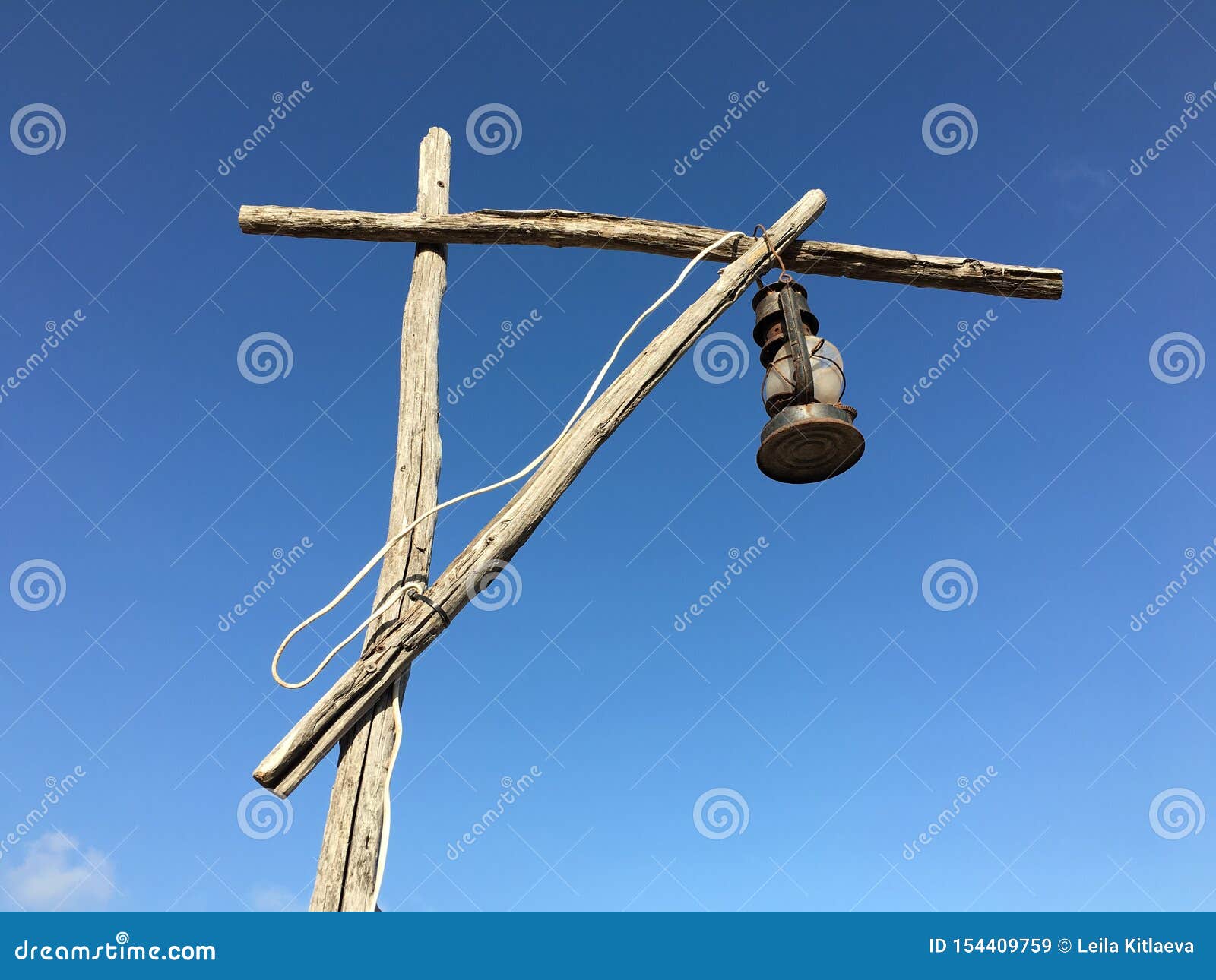 old rusty kerosene lamp with a white wire on a street wooden post crane