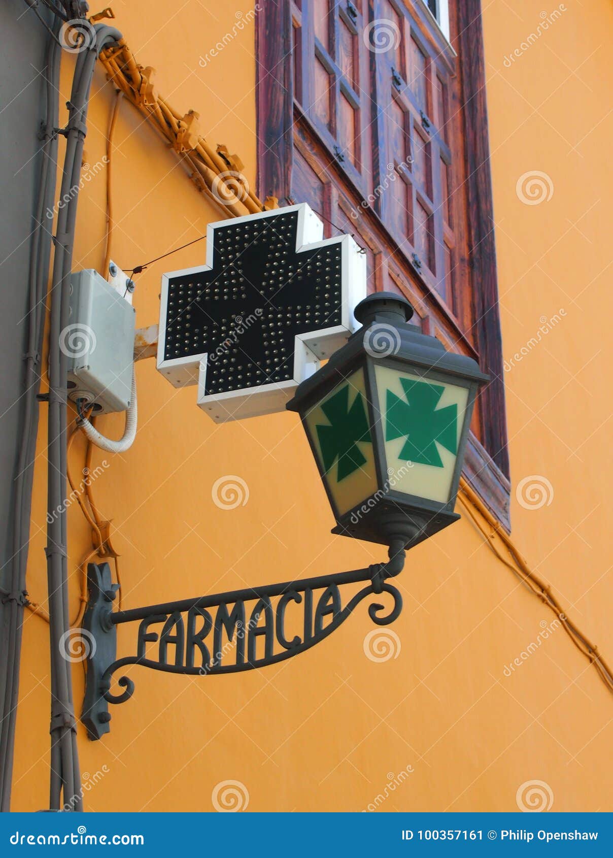 old spanish pharmacy sign in wrought iron on a yellow wall