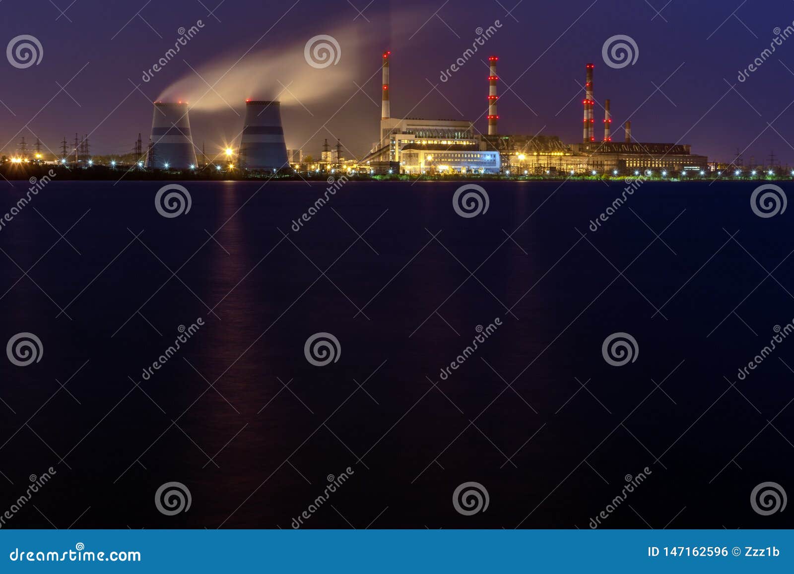 old thermal 450 megawatt power plant at night with artificial lake on foreground