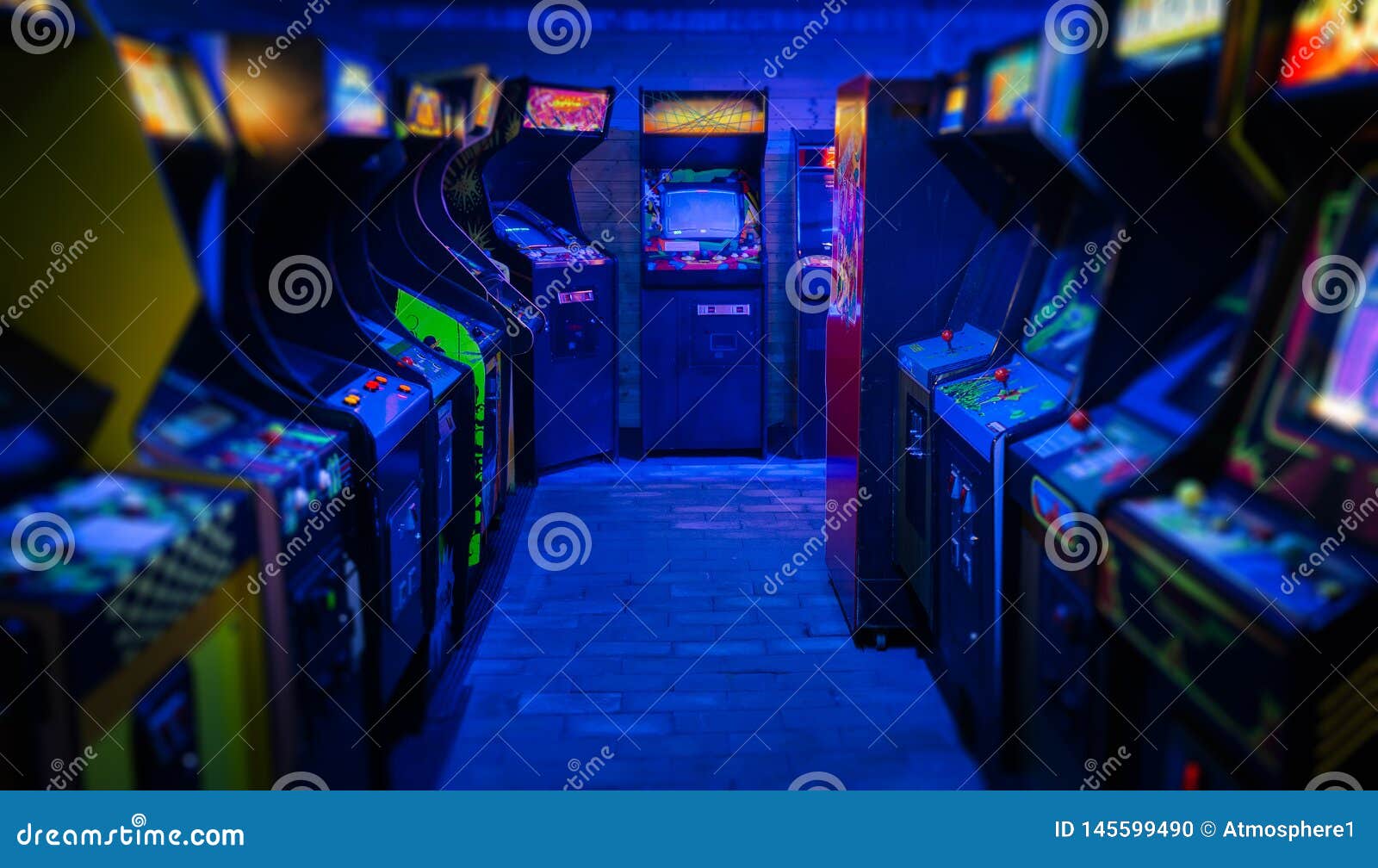 old vintage arcade video games in an empty dark gaming room with blue light with glowing displays