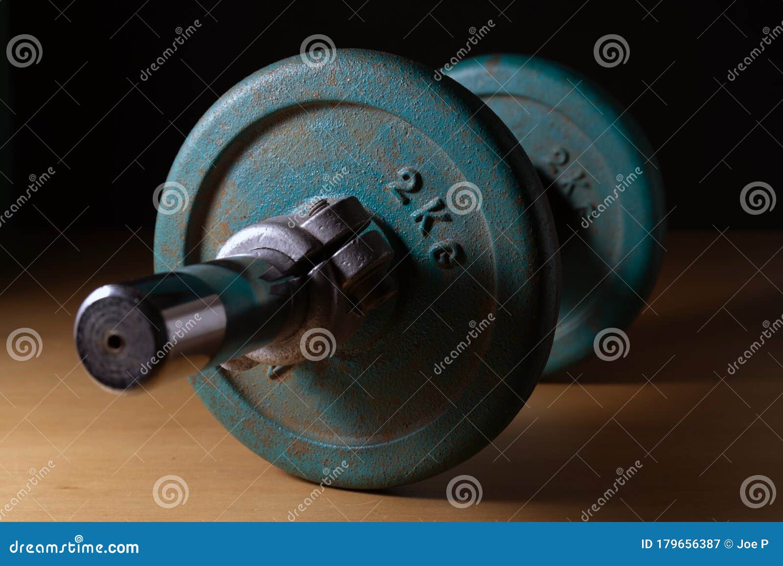 old vintage variable weight dumbbell over wood against black background