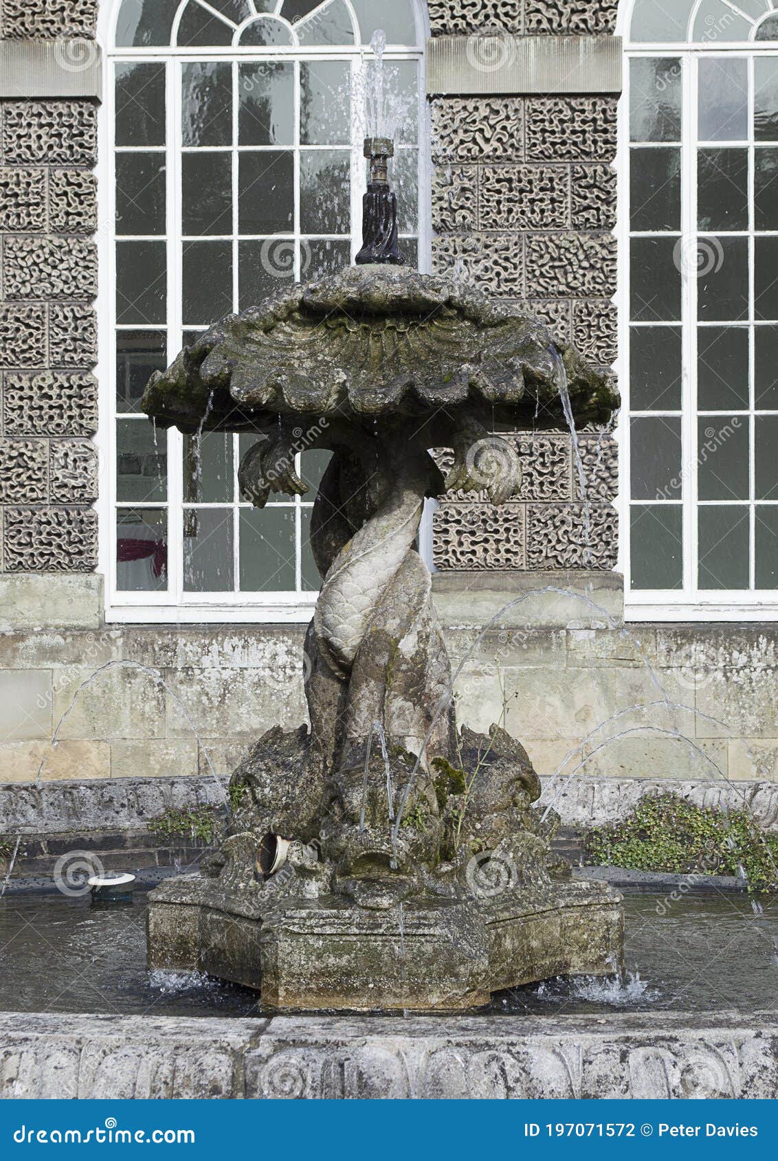 old water fountain with water surround in front of old stone walls and windows