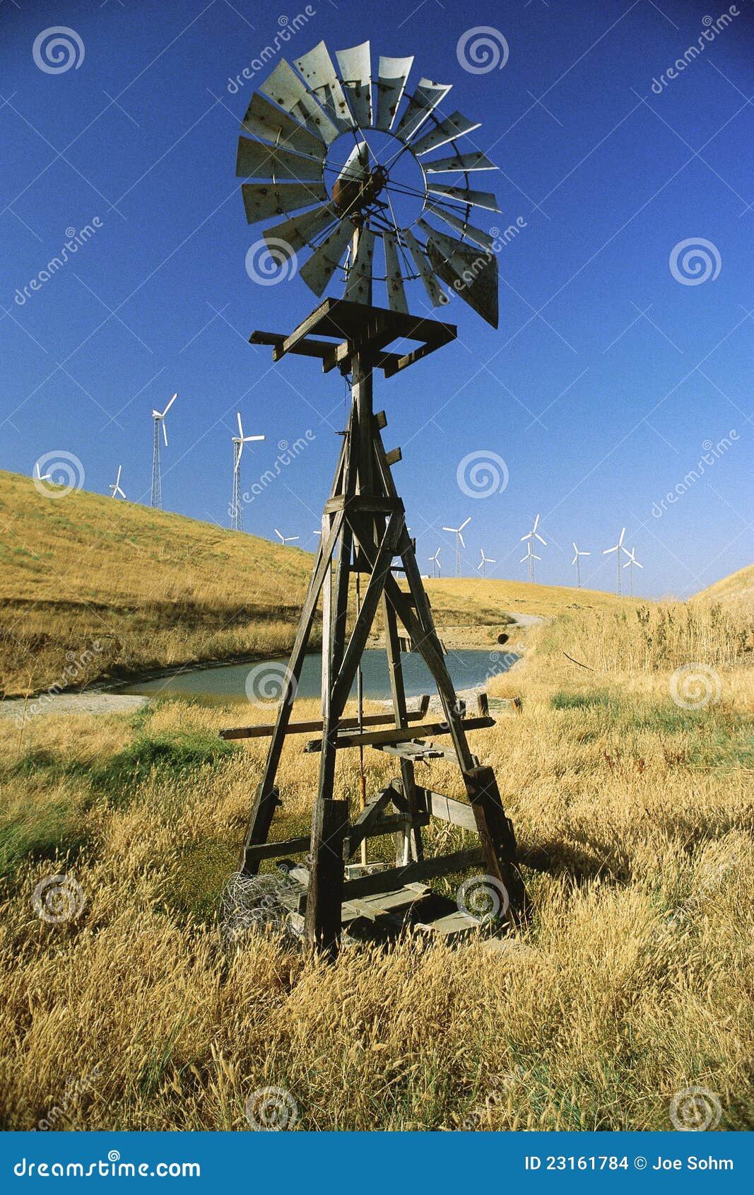 Old windmill with new windmills in background.