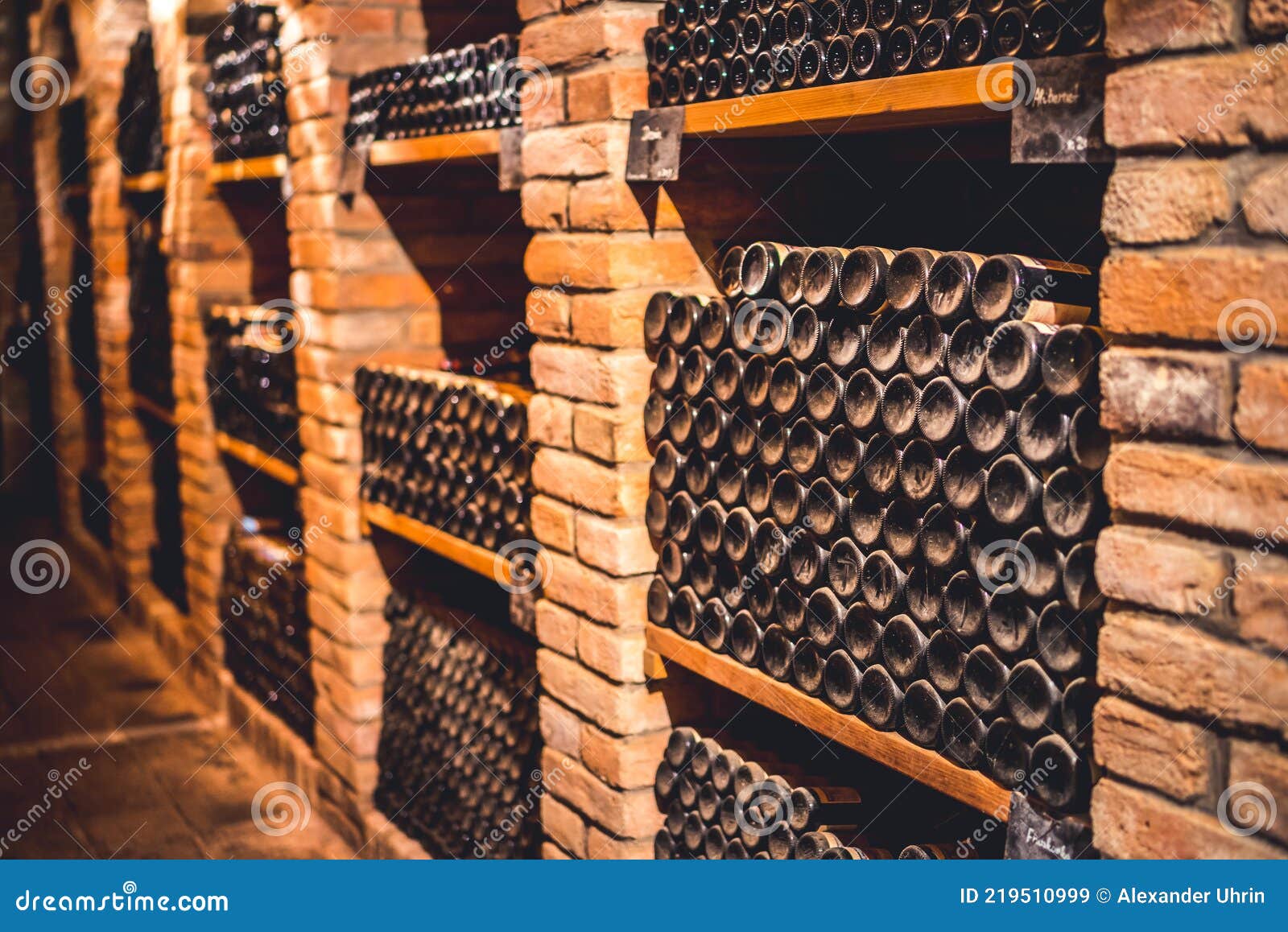 old wine bottles dusting in an underground tratitional cellar... small and old wine cellar with full wine bottles. winery concept.