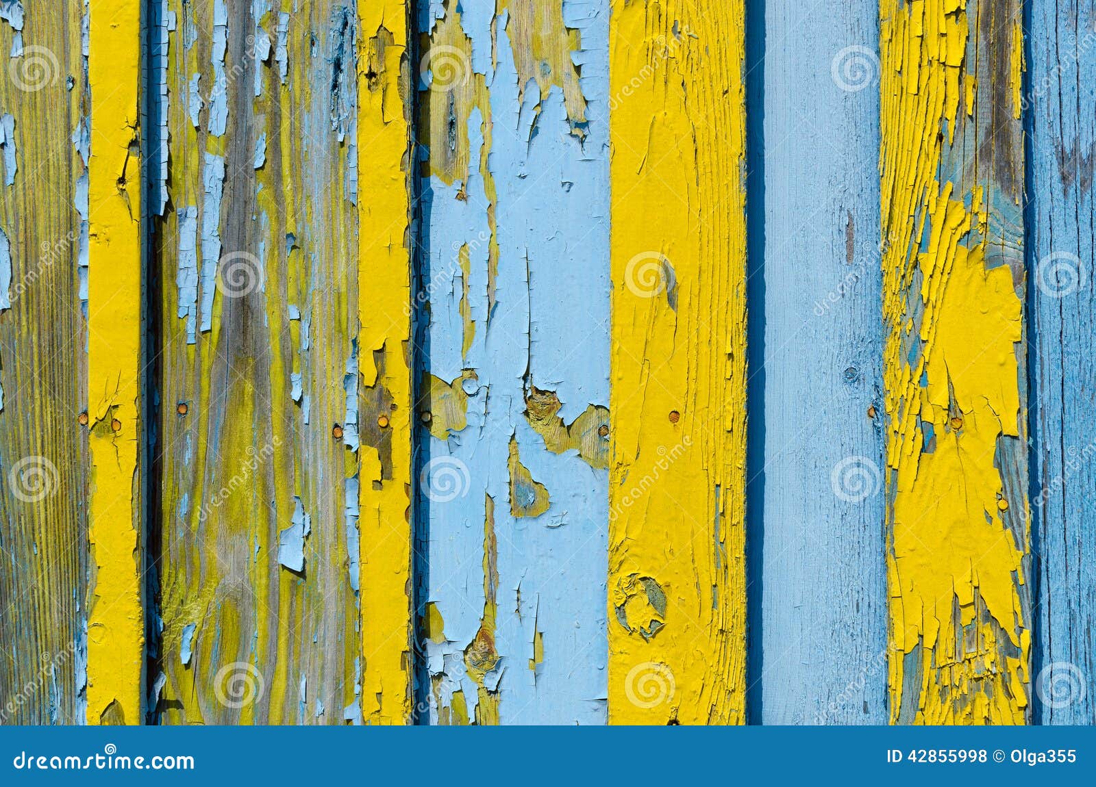 Old wooden fence with cracked paint. Old wooden fence with cracked yellow and blue paint, background