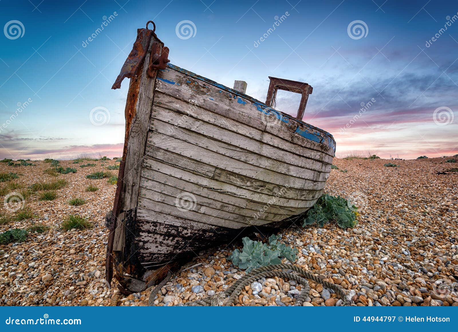 Old Wooden Fishing Boat. An old abandoned wooden fishing boat high on a shingle beach