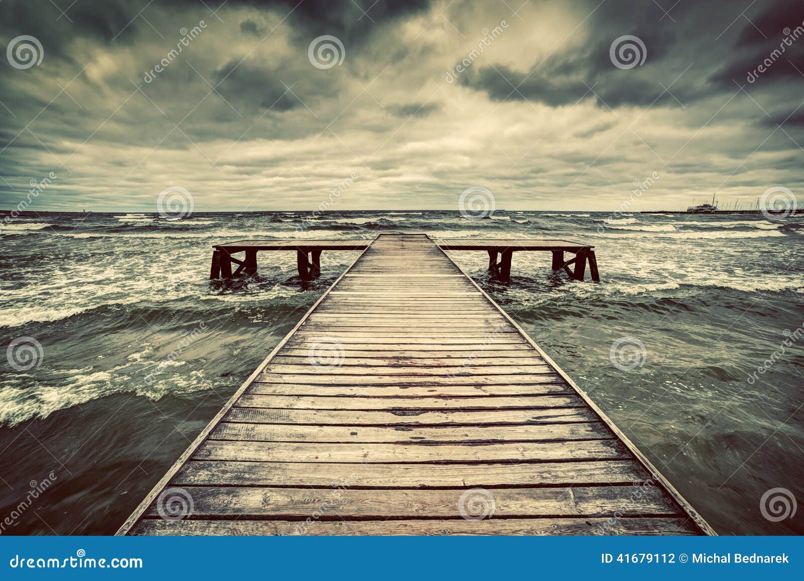 old wooden jetty during storm on the sea. dramatic sky with dark, heavy clouds