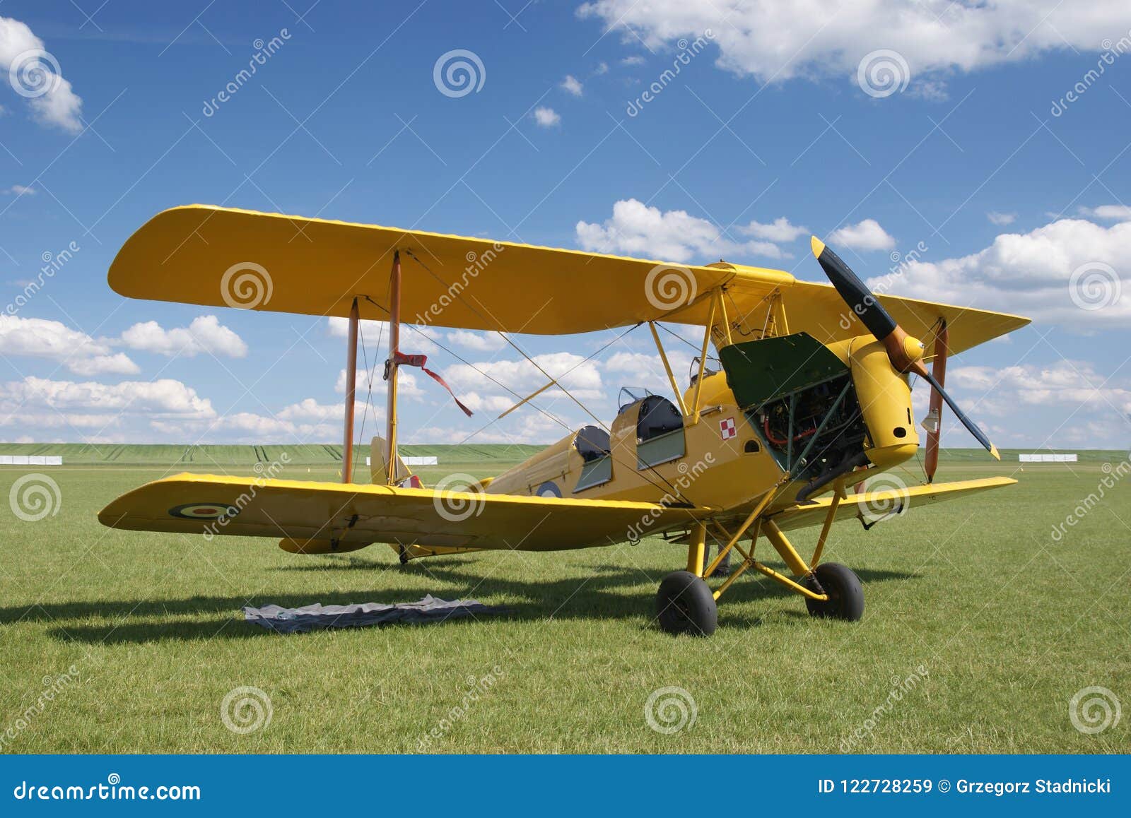 An old yellow biplane airplane from the early 20th century. Waiting for the start at the air show at the grass airport.