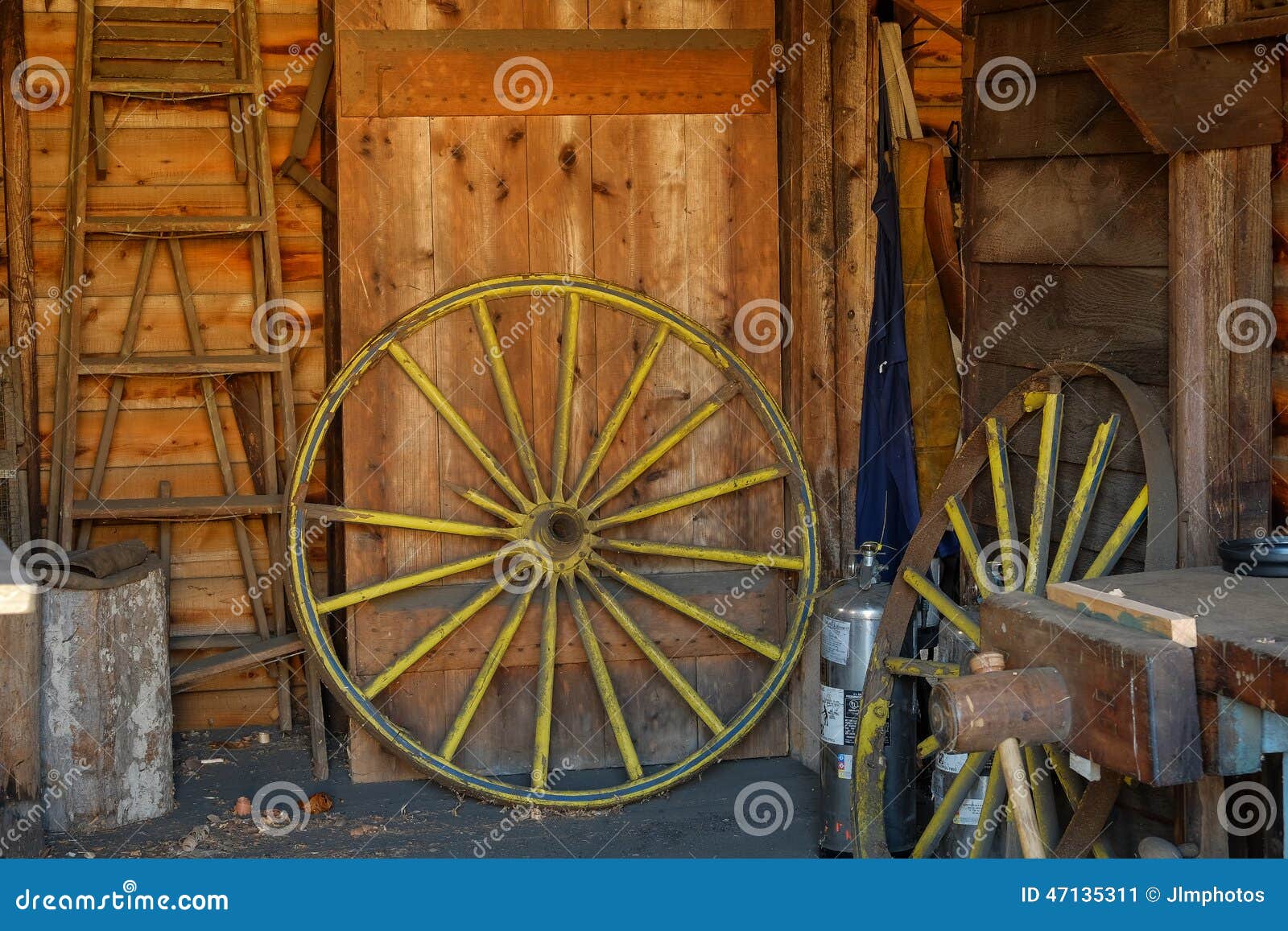 Old Yellow Wagon Wheel Waiting For Restoration In An Old Barn