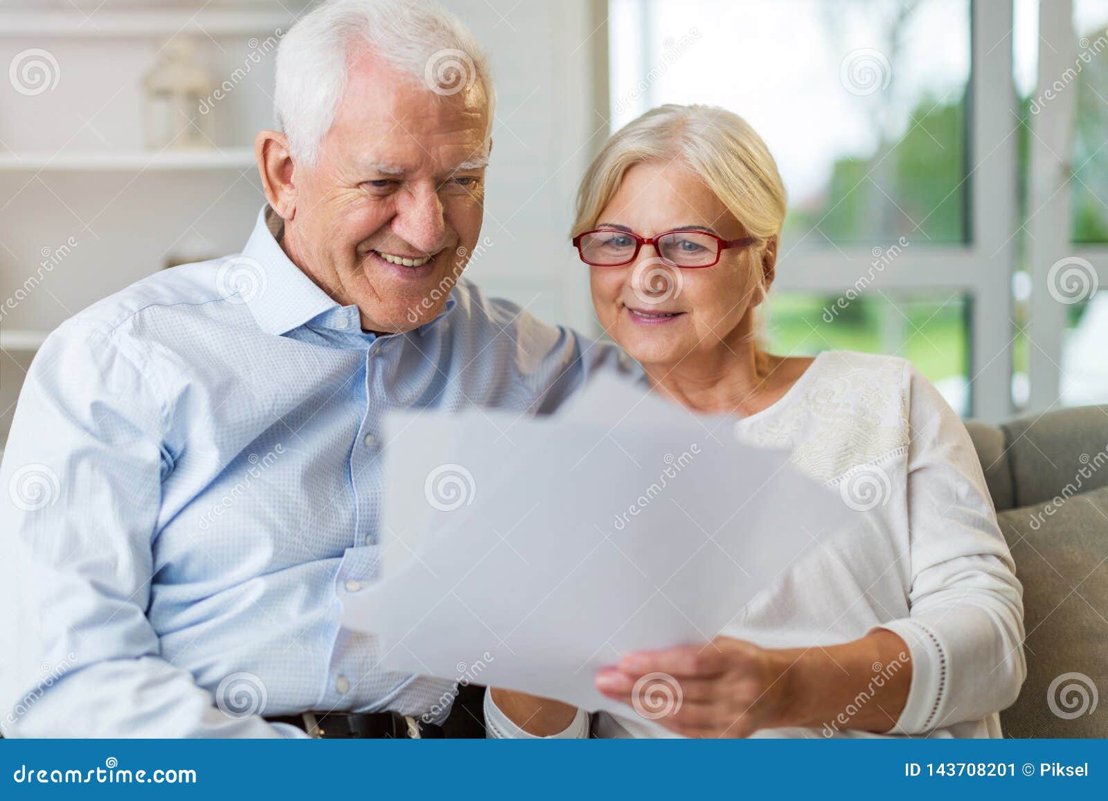 older couple reading papers together on sofa