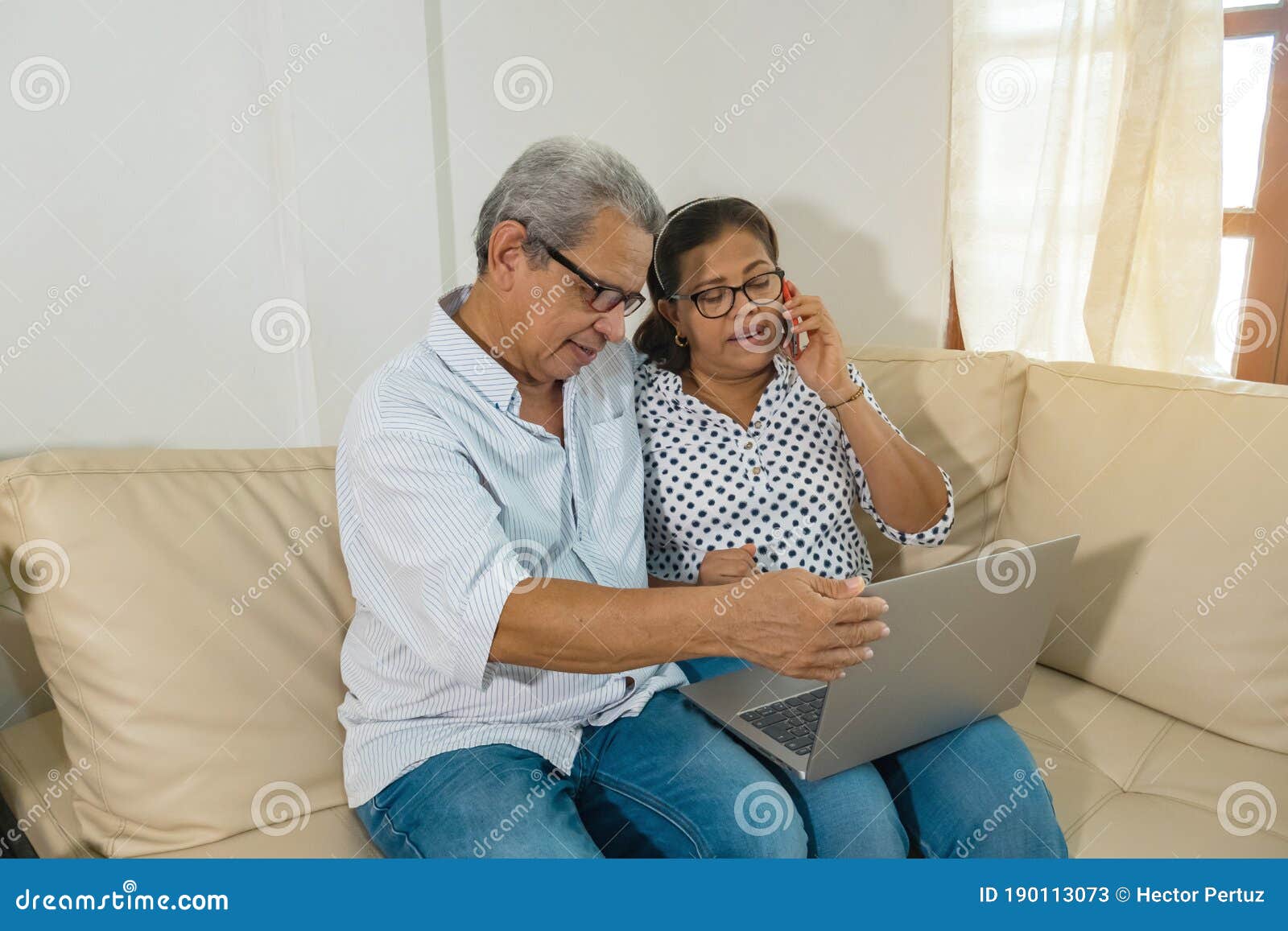older latino web-surfing couple with laptop and cell phone.
