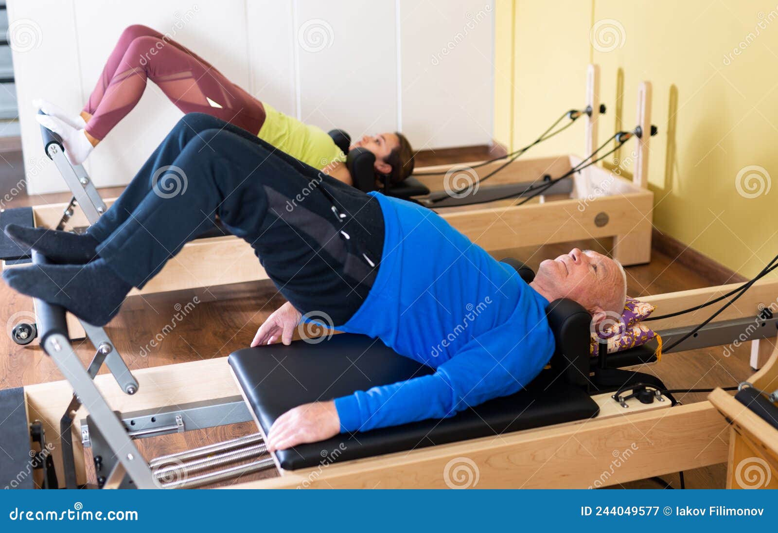 older man doing exercises of remedial gymnastic on pilates reformer