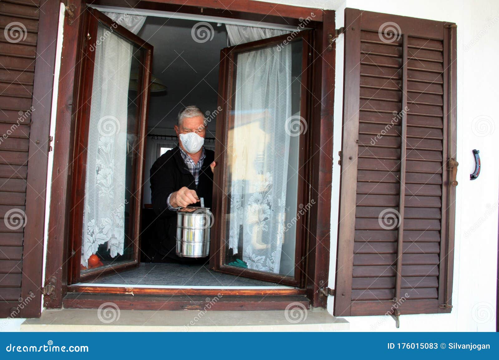 older person getting food container through open window