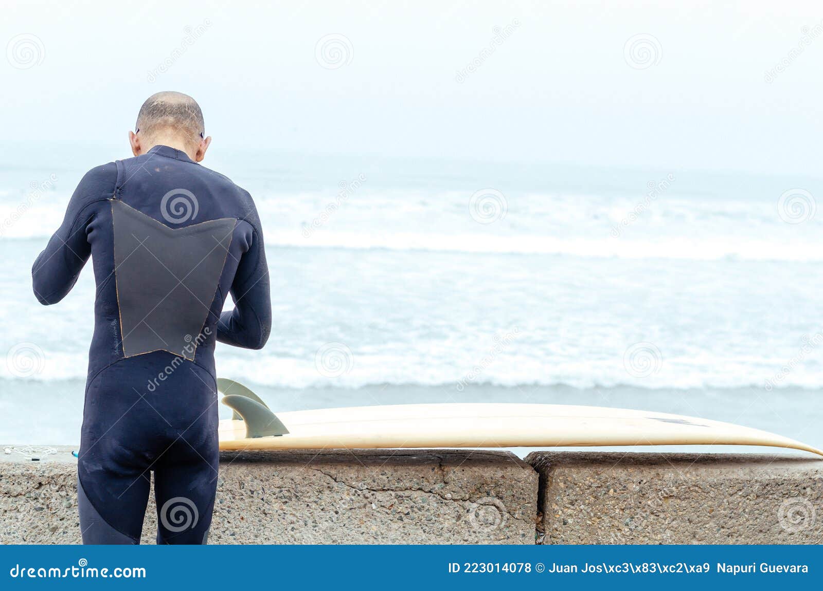 Older Surfer on His Back, with a Surfboard and the Sea in the