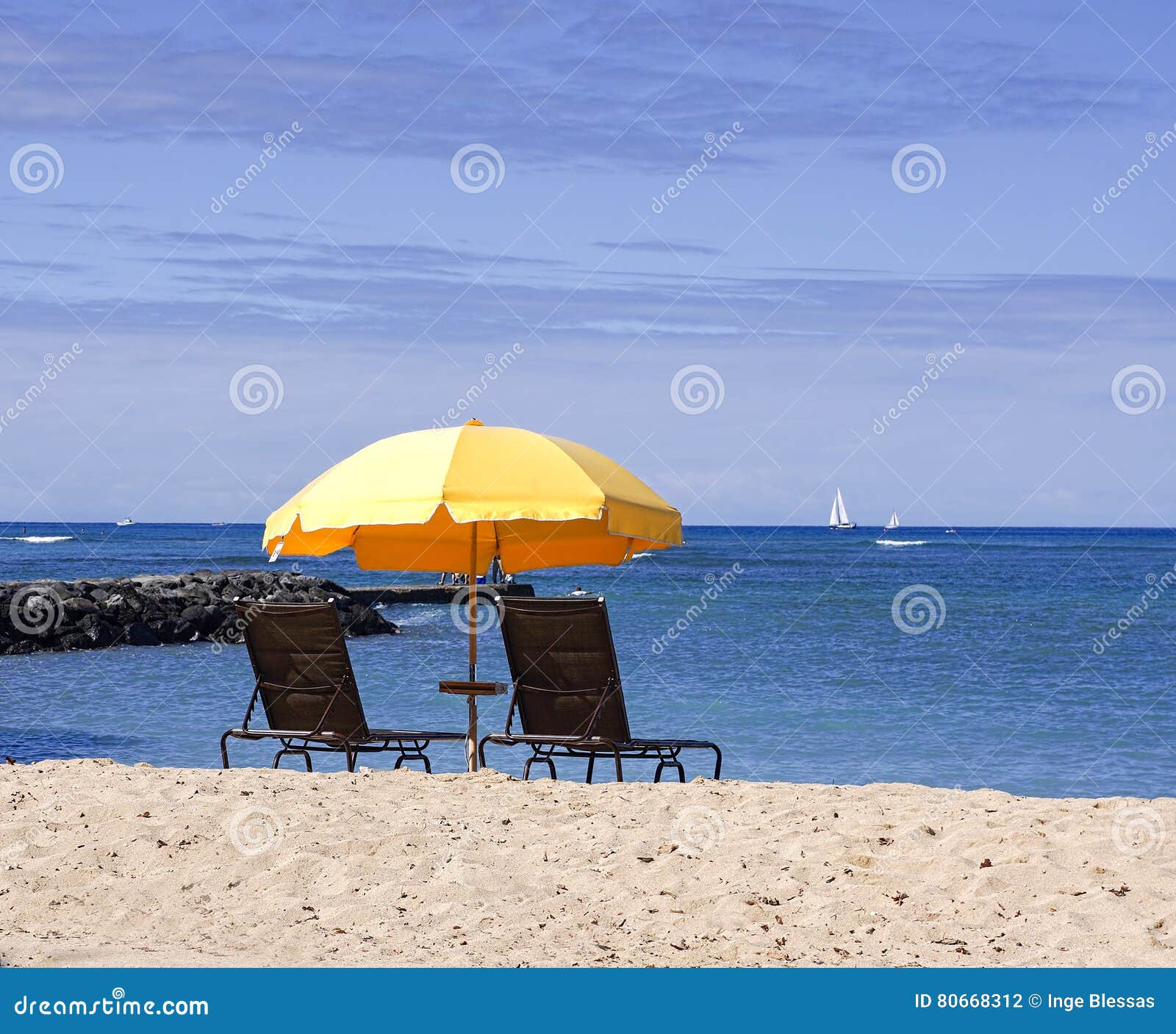 Ombrello di spiaggia giallo con gli sdrai sulla spiaggia sabbiosa con il mare ed il cielo blu