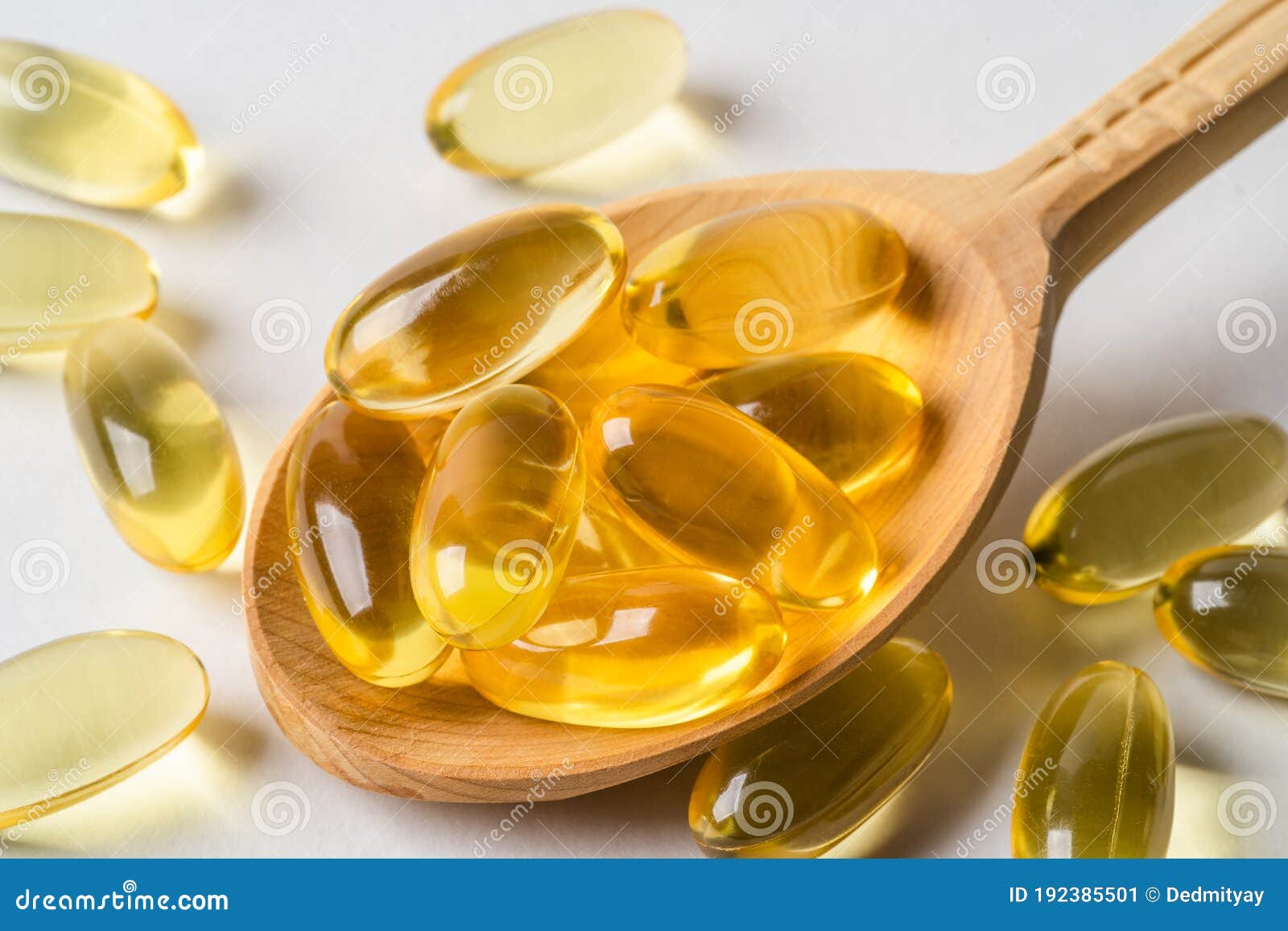 omega 3 yellow capsules in wooden spoon on white background. epa and dha are two types of omega-3 fats essential fatty