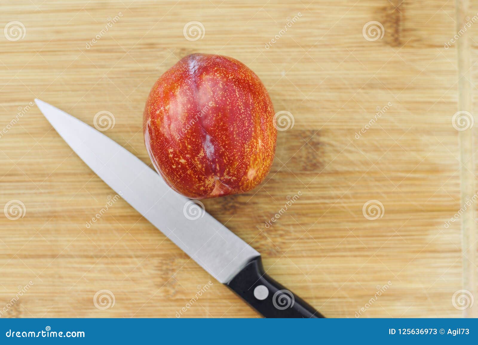 one amigo pluots on a wood chopping board with a knife