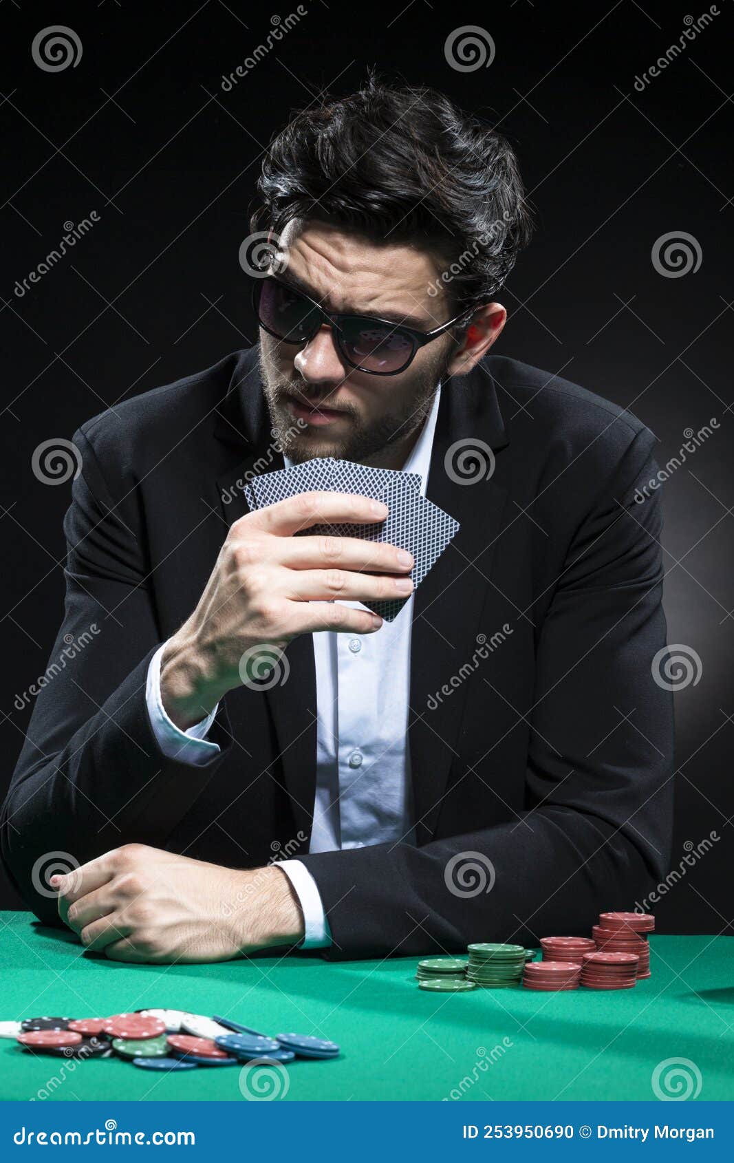 caucasian brunet pocker player at pocker table with chips and cards while thoughfully sitting