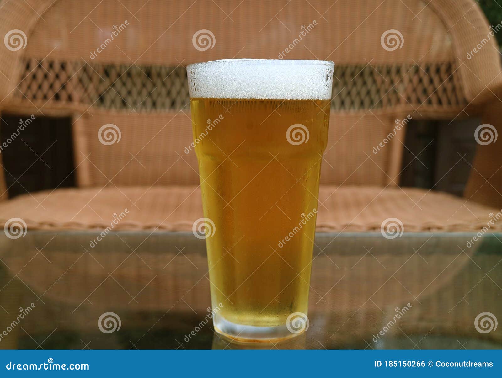 One Glass of Chilled Beer Isolated on the Table with Blurry Empty Chair
