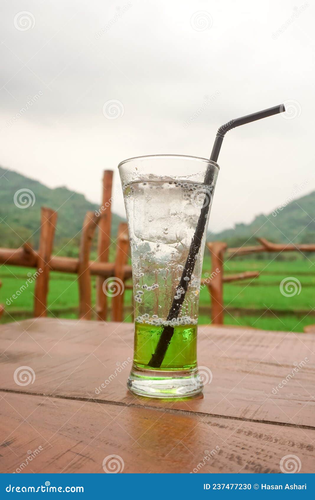 One Glass of Fresh Melon Squash Drink on a Table with Rice Fields and