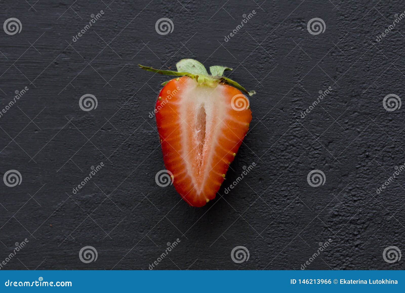 one half of strawberry, cut red beautiful strawberry close-up, on a black dark concrete background. macro shooting. fruit erotica
