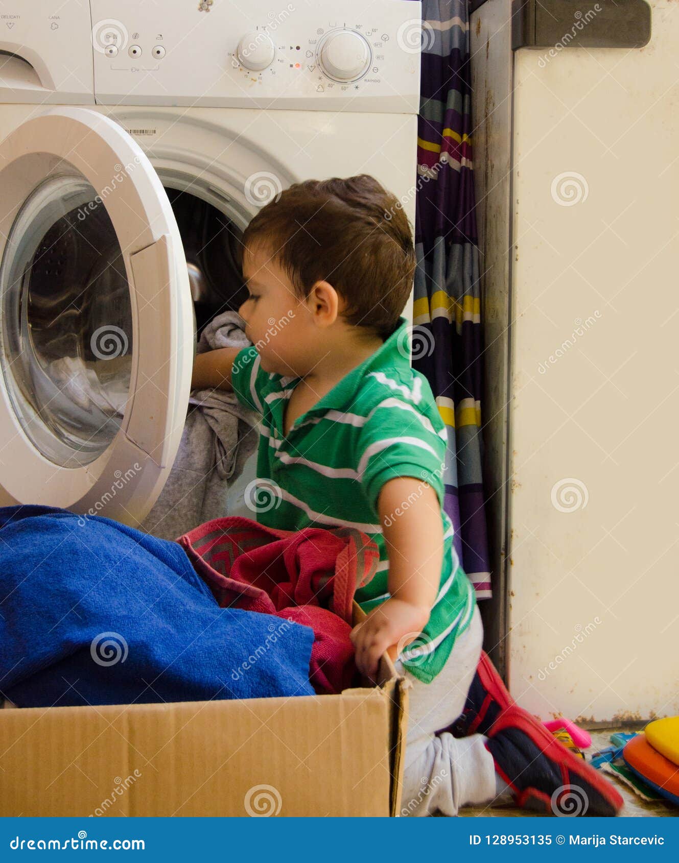 One and the Half Years Old Baby Boy Putting Clothes in Washing Machine