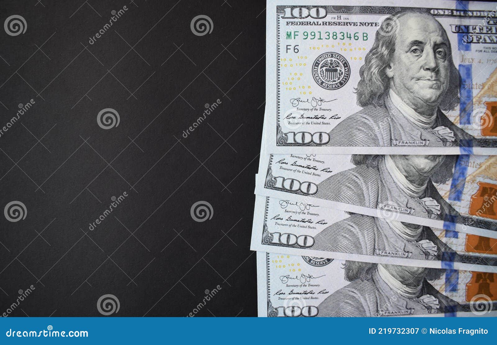 one hundred dollar bills on black background