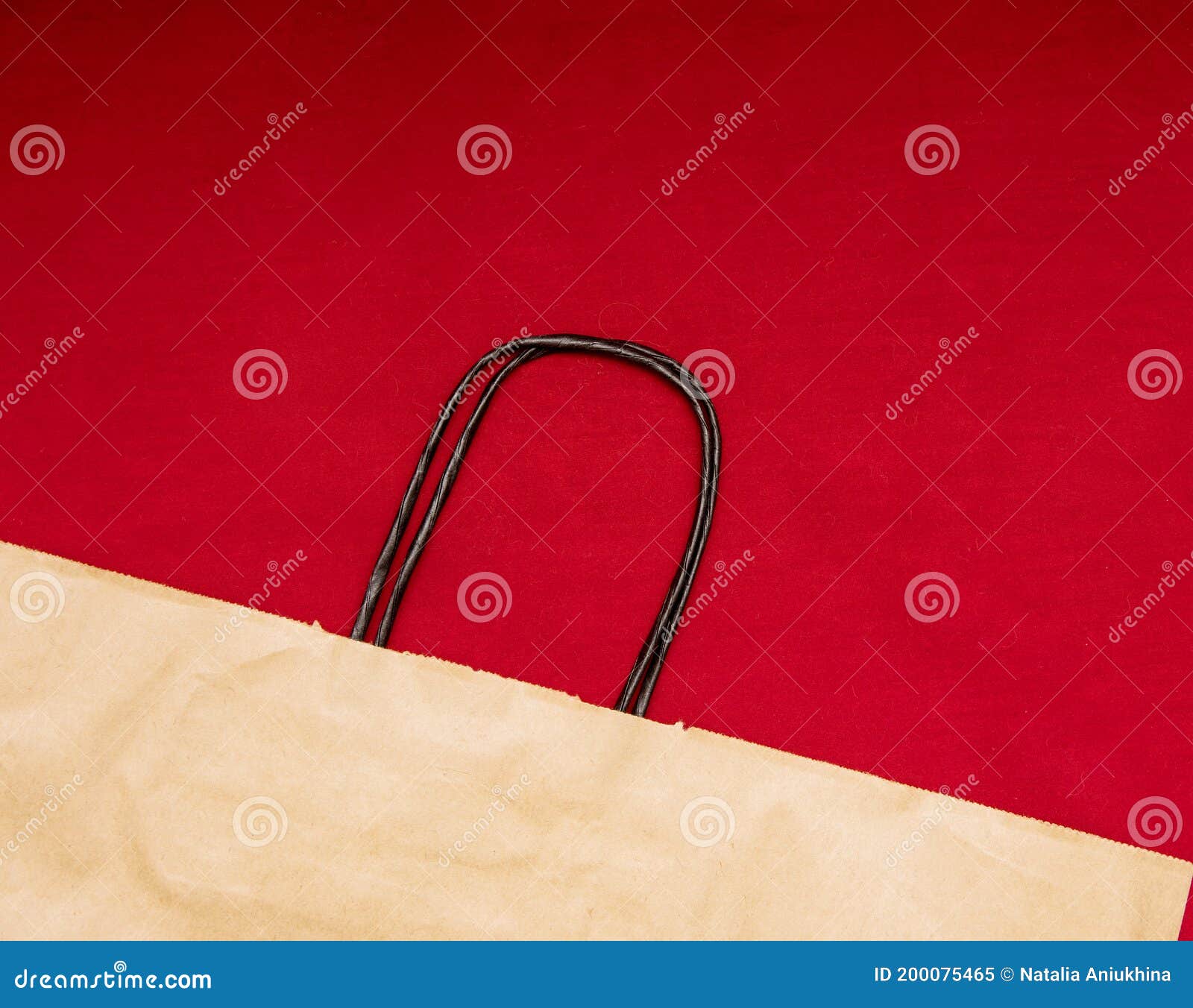 One Kraft Paper Recyclable Bag with Handles Lie on a Red Background