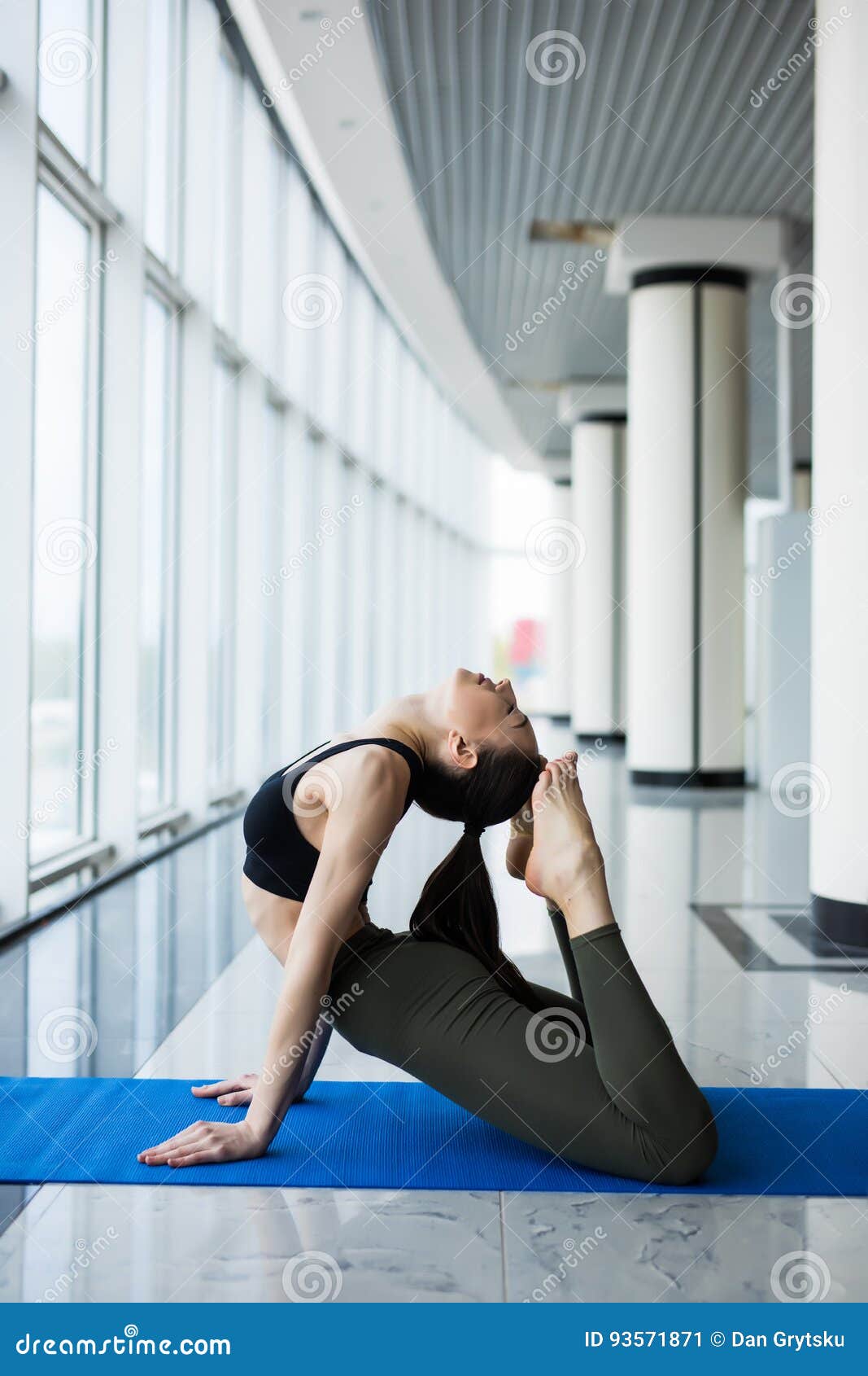 one-legged king pigeon pose. woman yoga practice pose training concept in gym hall with big windows