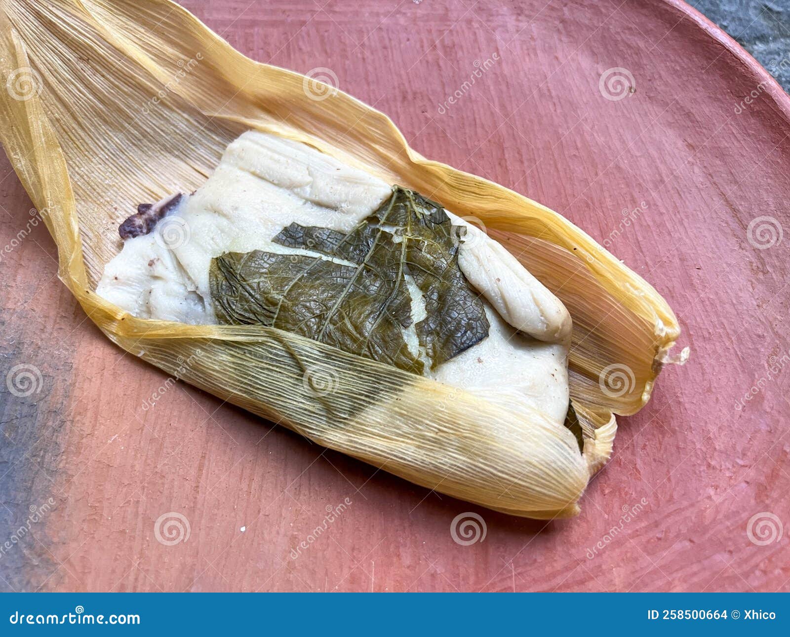 one oaxacan tamale with hoja santa wrapped on the outside of the masa