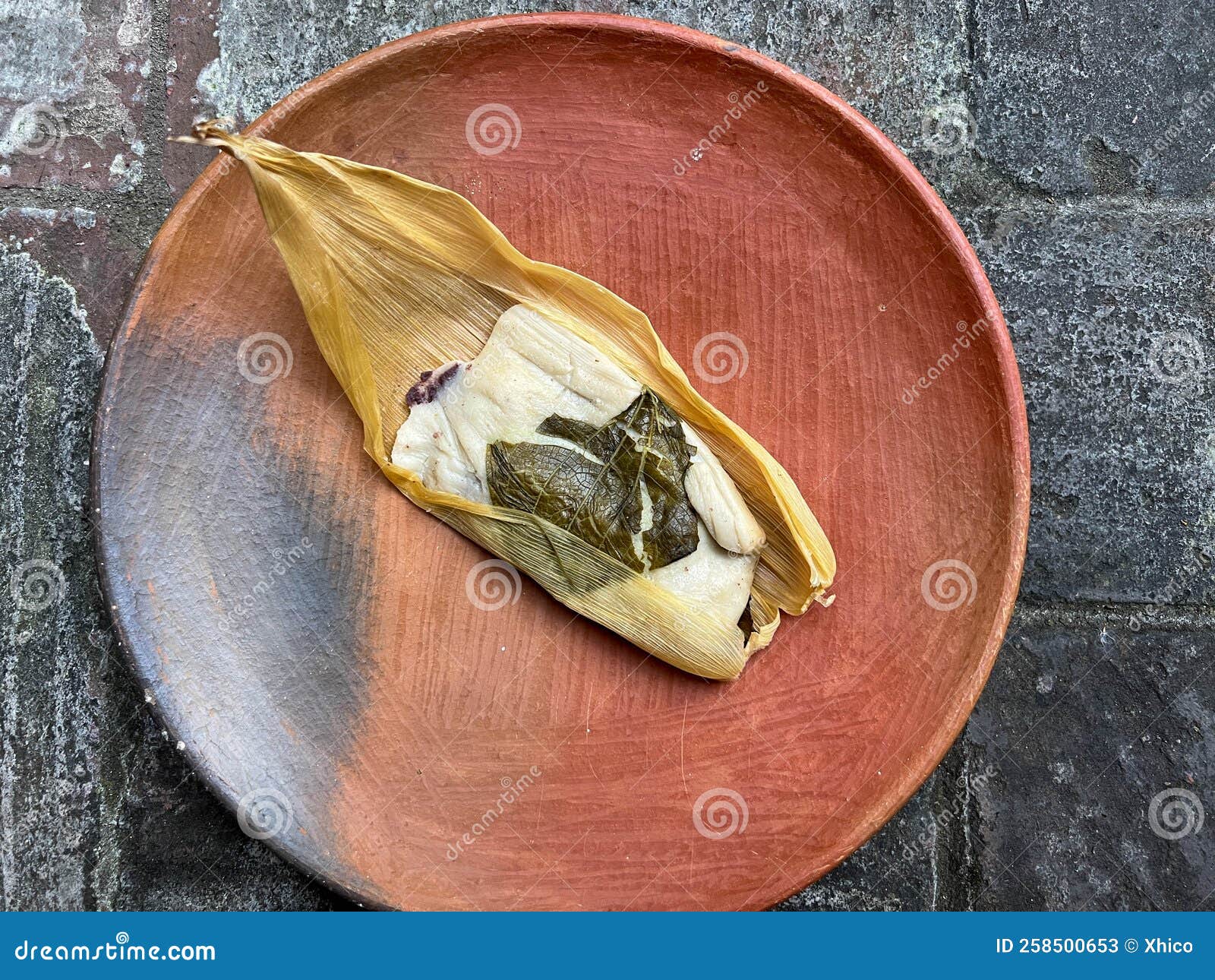 one oaxacan tamale with hoja santa wrapped on the outside of the masa
