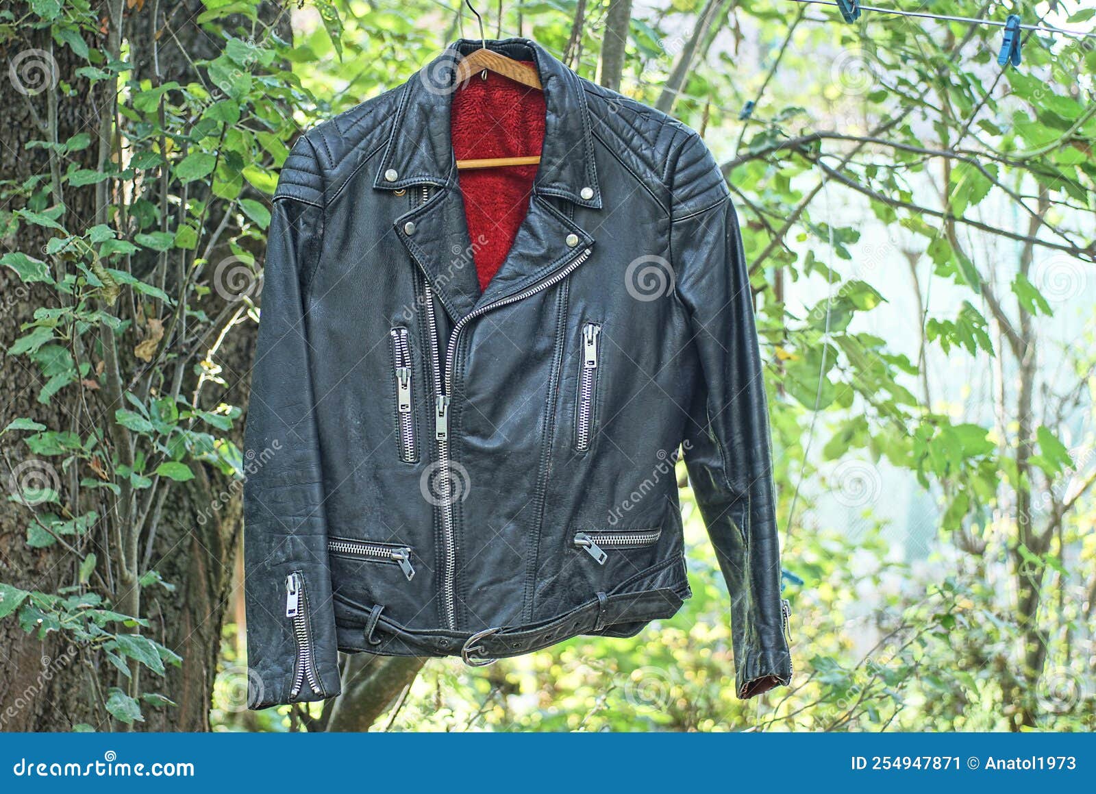 One Old Black Leather Jacket with Red Lining Hangs on a Wire Stock