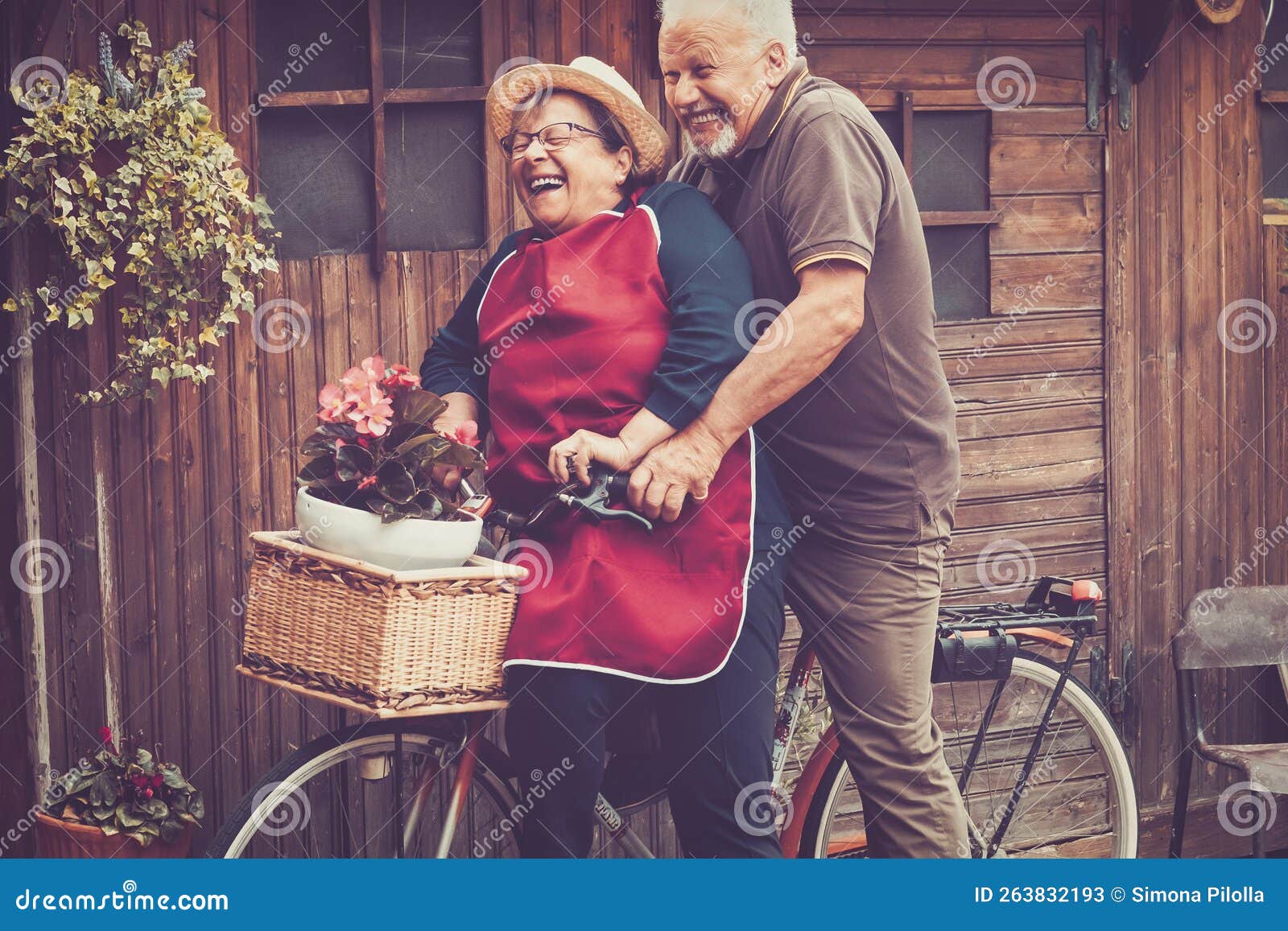 one old senior couple have fun together playing and joking outdoor on a bike. active mature man and woman aging youthfully with