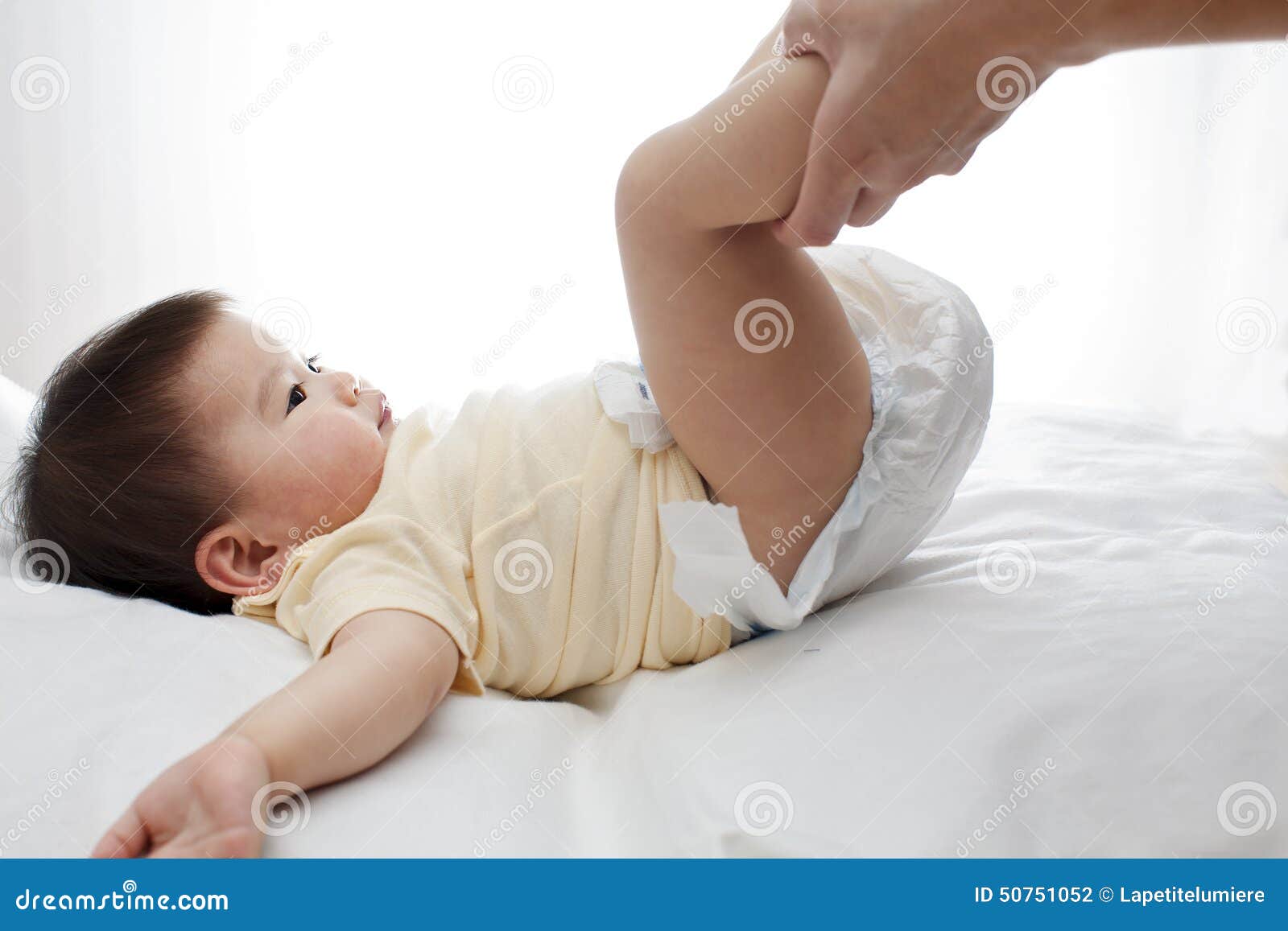 a small cute little baby girl was lying down, her diaper was being changed by her dad