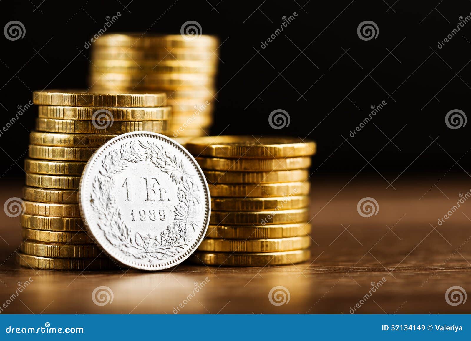 one swiss frank coin and gold money on the desk