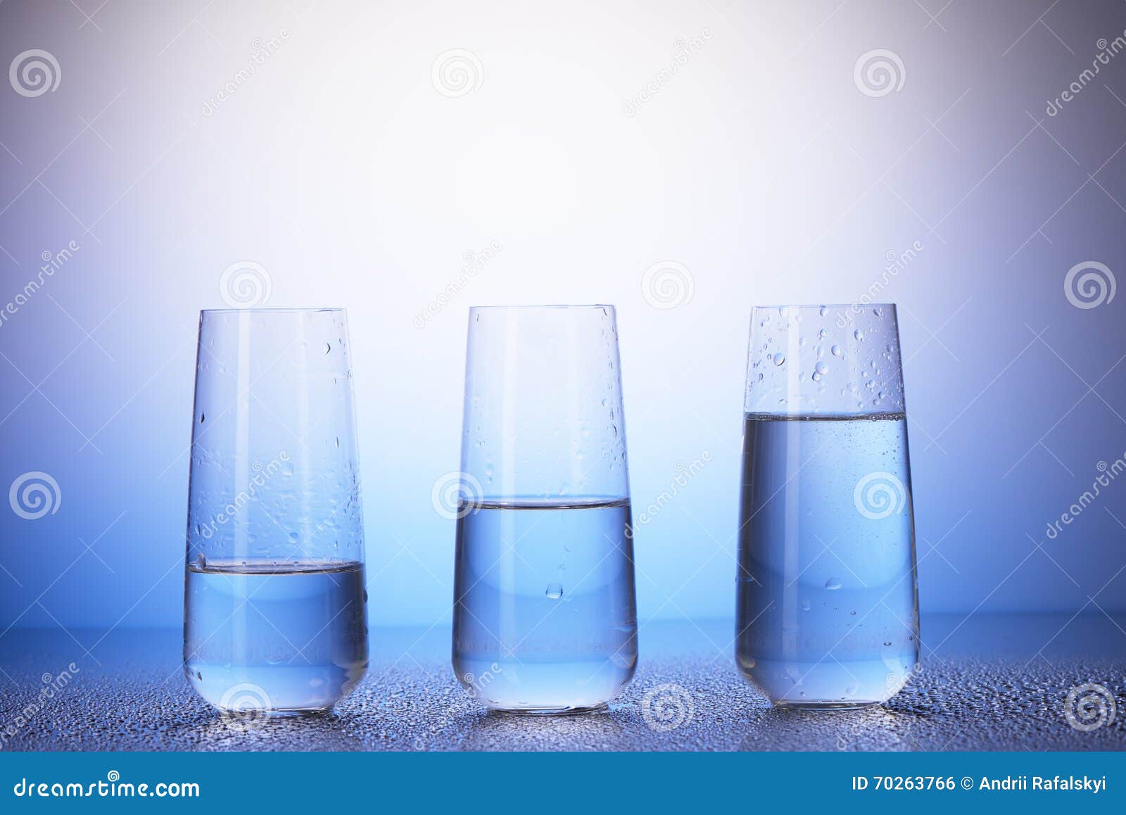 one-third, half-filled and two-thirds full drinking glasses
